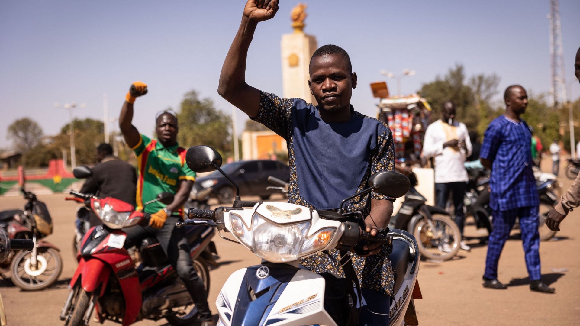 Un homme assis sur sa moto fait des gestes alors que les gens se rassemblent sur la place de la Nation pour soutenir les militaires à Ouagadougou, le 24 janvier 2022.