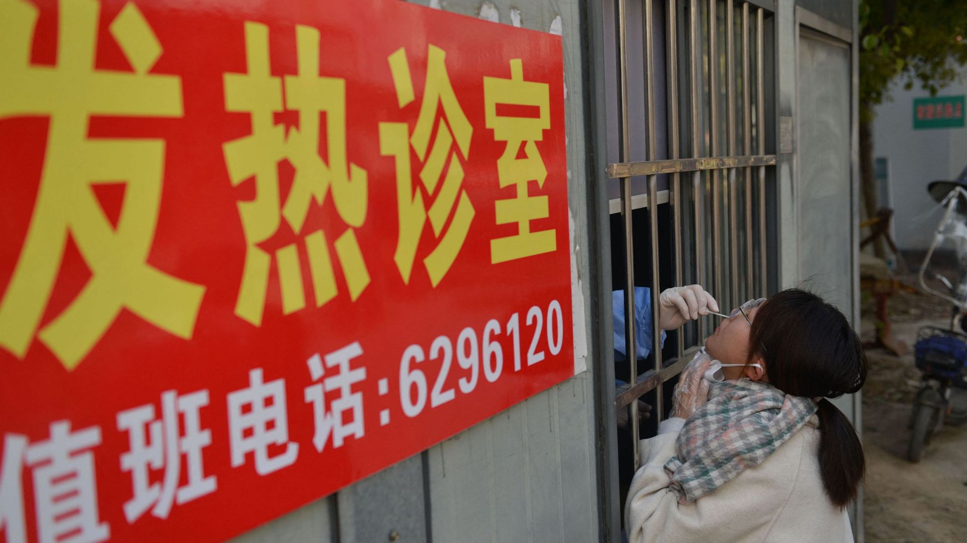 Cette photo prise le 15 décembre 2022 montre un agent de santé prélevant un échantillon par écouvillonnage sur une femme afin de la soumettre à un test de dépistage du coronavirus Covid-19 dans une clinique de la fièvre à Fuyang, dans la province chinoise