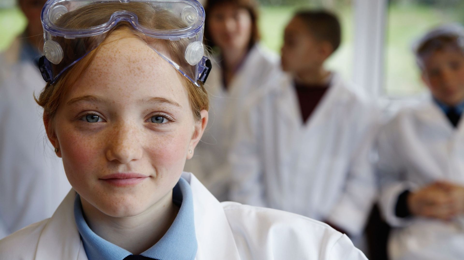 Schoolgirl (11-13) in science class, smiling, portrait (focus on girl)