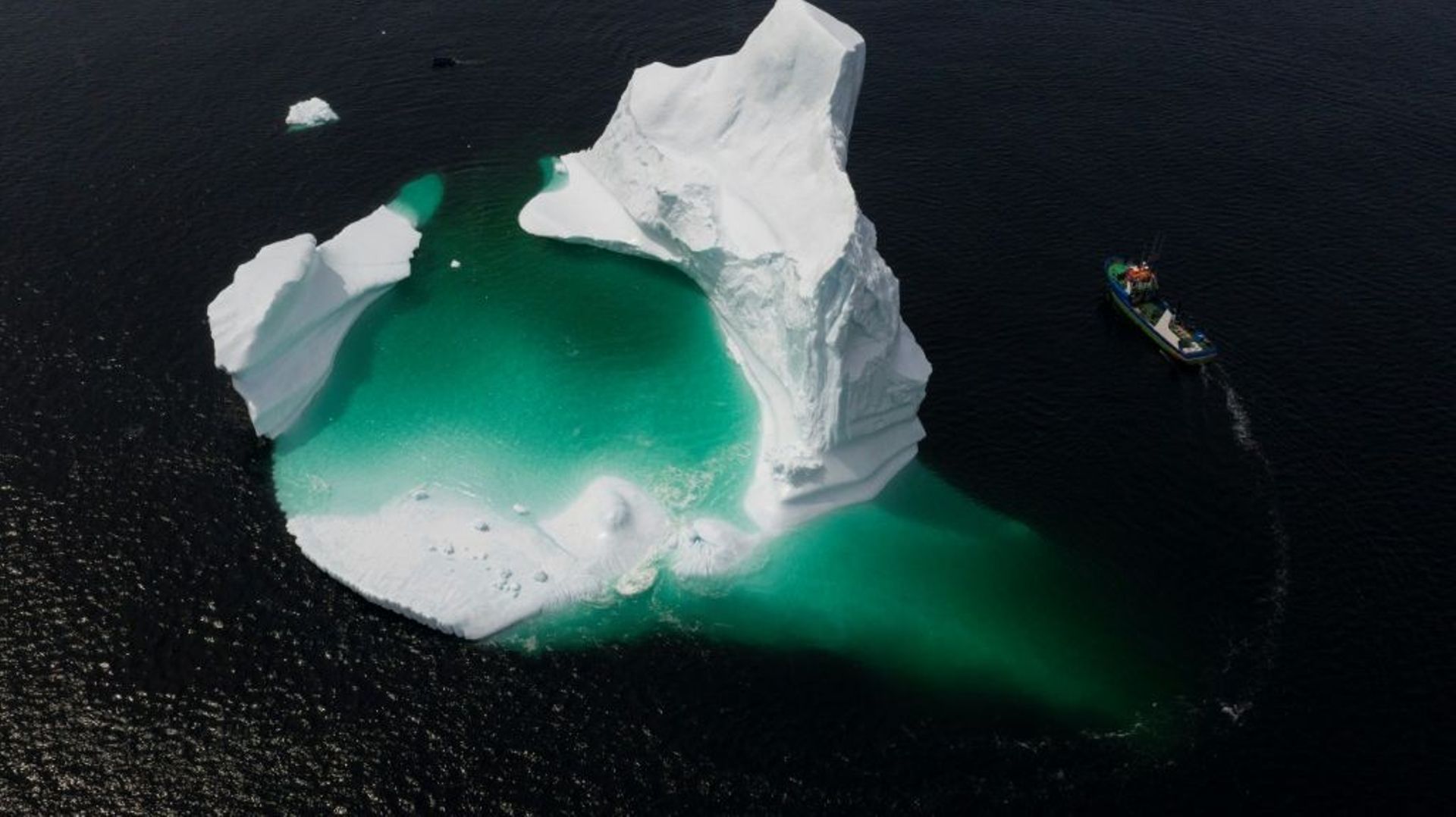 Un bateau contourne un iceberg dans les eaux du Canada en 2019