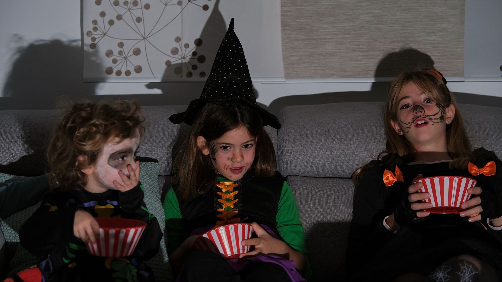 Friends watching a movie on Halloween while eating popcorn