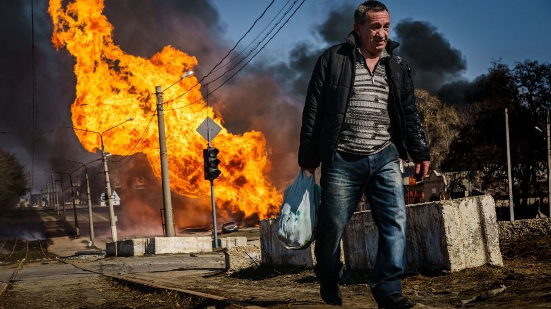Un homme se dépêche de s'éloigner d'un bâtiment qui vient d'être touché par un bombardement russe et qui a pris feu, dans le quartier Moskovskyi de Kharkiv, en Ukraine, vendredi 25 mars 2022.