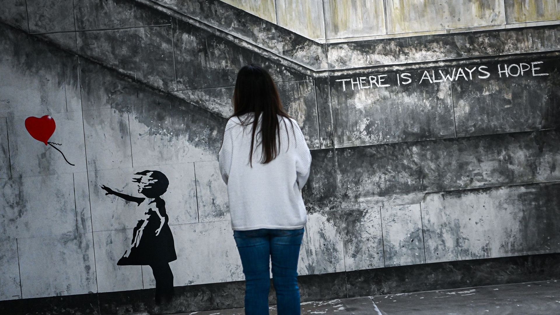 Une femme regarde une œuvre d’art intitulée " There is Always Hope " (Il y a toujours de l’espoir) de Banksy lors de l’ouverture de l’exposition " The World of Banksy at The Immersive Experience " (Le monde de Banksy à L’expérience immersive) à la gare ce