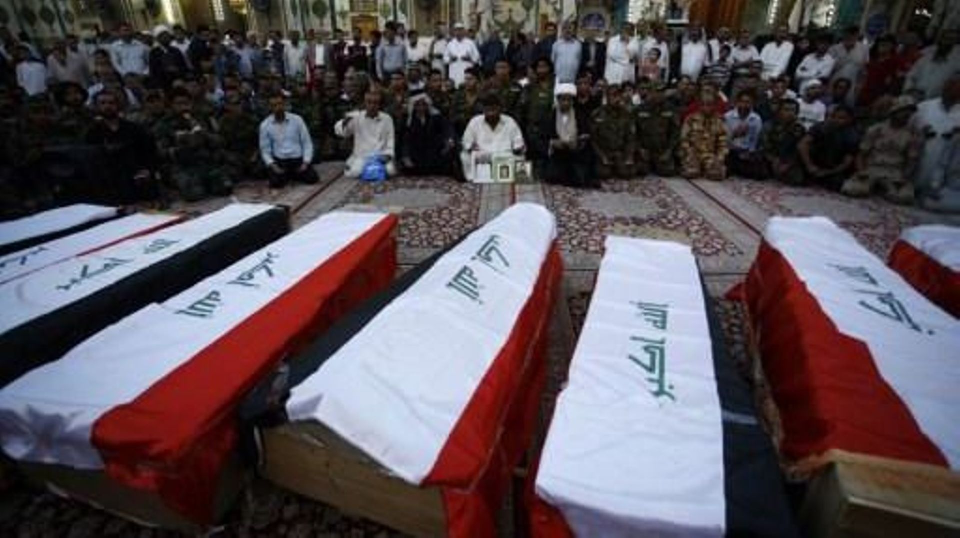 Des civils et des soldats irakiens pleurent à côté des cercueils contenant les restes de dix de leurs camarades tués lors du massacre de Speicher