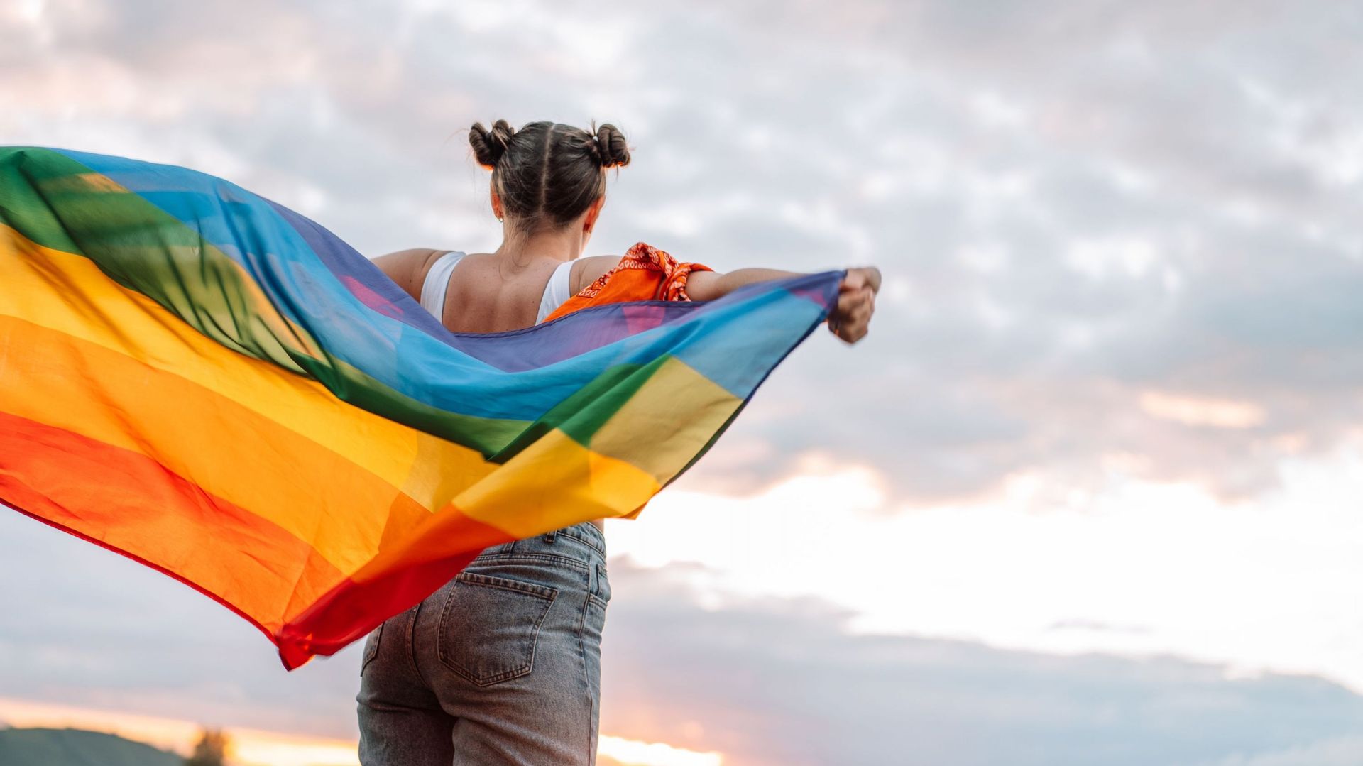 Jeune femme tenant le drapeau LGBT dans le vent. Copyright :