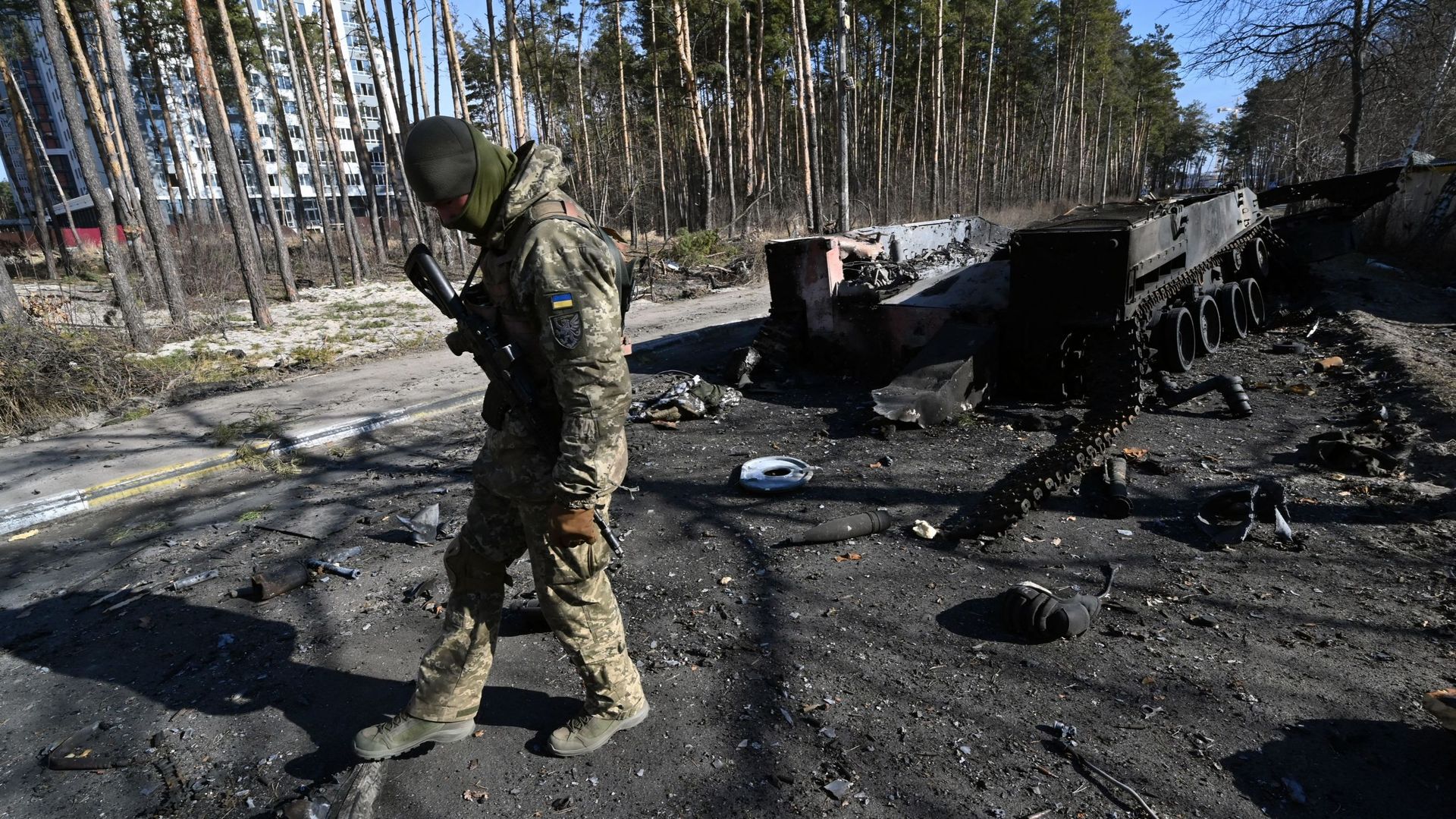 Un soldat ukrainien examine l’épave d’un véhicule blindé de transport de troupes russe détruit à Irpin, au nord de Kiev, le 12 mars 2022.