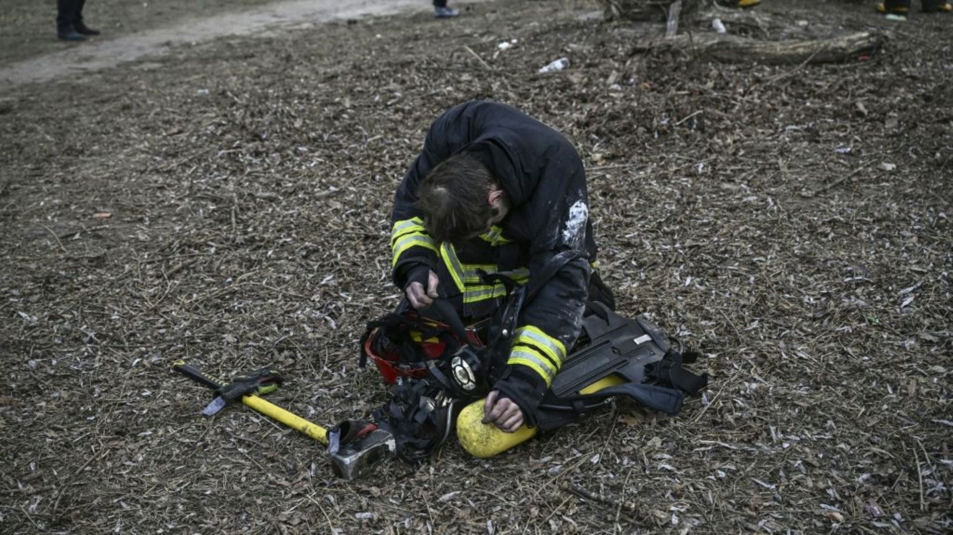 Un pompier ukrainien épuisé devant un immeuble d’habitation incendié par un bombardement russe à Kiev, le 15 mars 2022