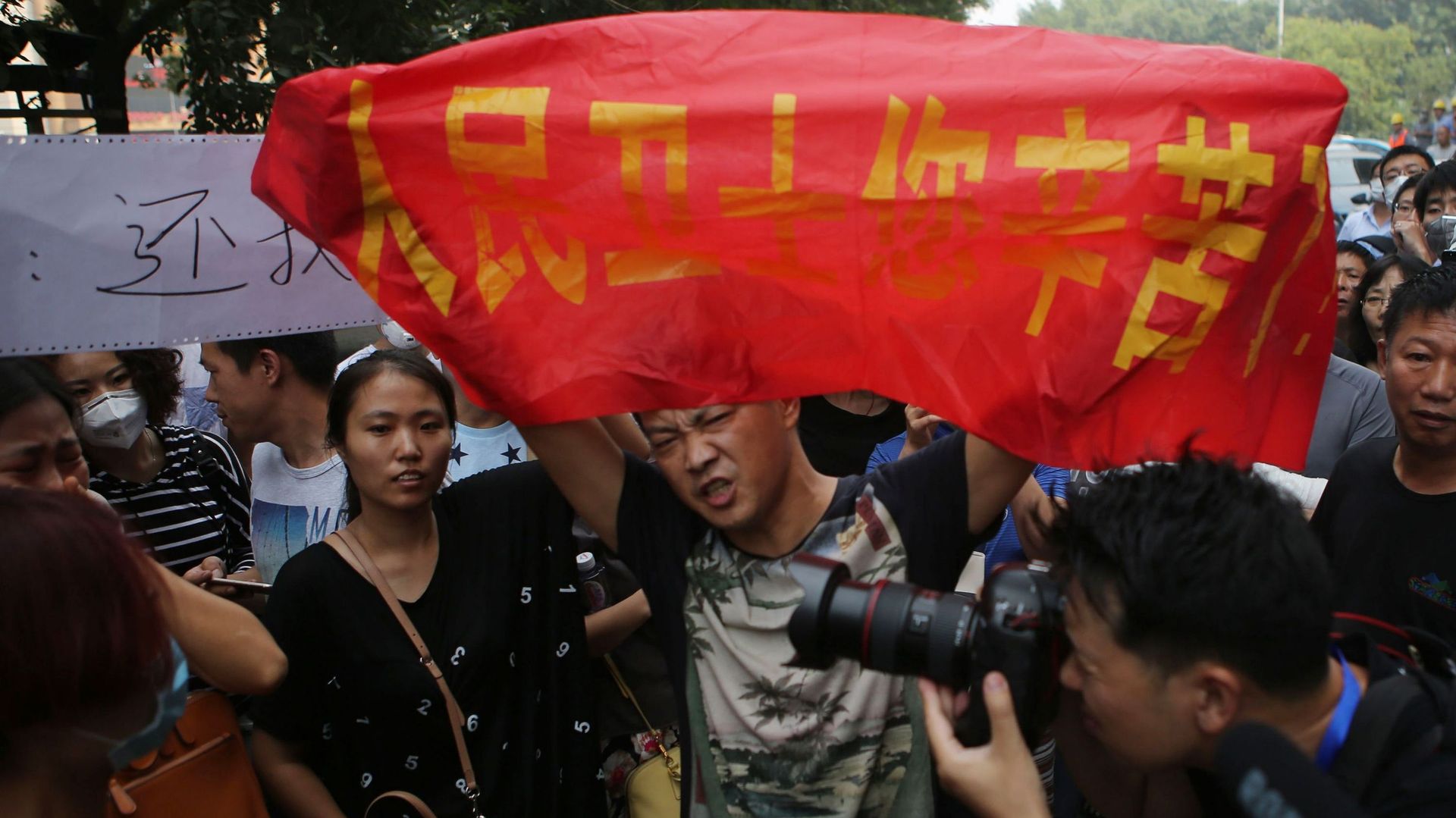 Des manifestants expriment leur colère à l'extérieur du bâtiment où les autorités chinoises tiennent une conférence de presse