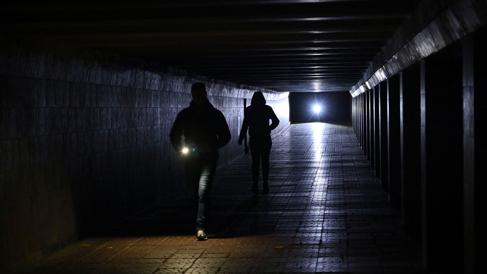 Des personnes utilisent des lampes de poche alors qu’elles traversent un passage souterrain non éclairé dans le centre de Kiev, le 27 octobre 2022.