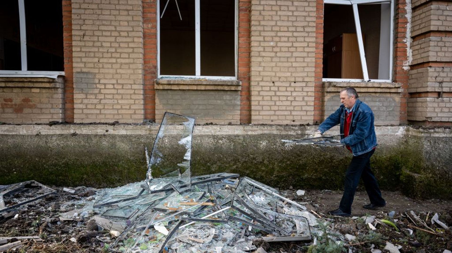 Des Ukrainiens nettoient après les attaques russes sur une école.