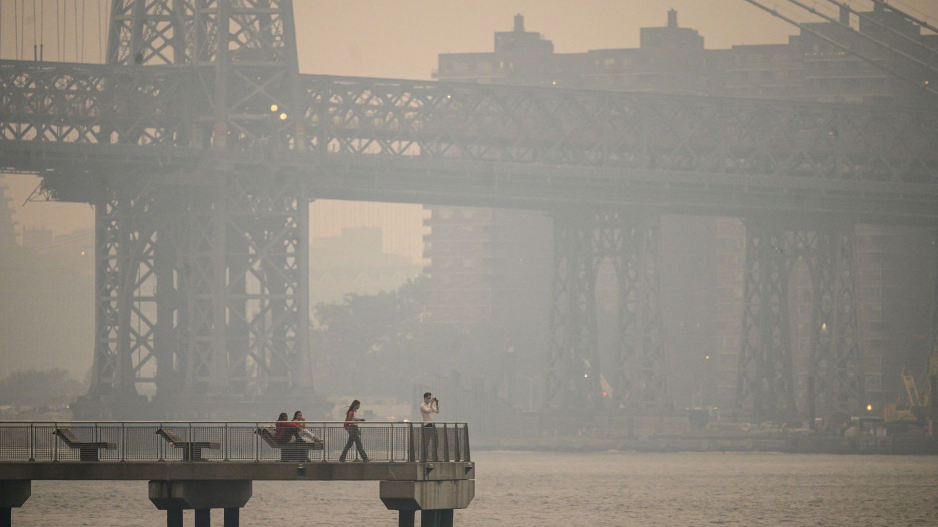 Des personnes se tiennent sur une jetée de la ville de New York enveloppée de fumée, à Brooklyn, le 6 juin 2023.
