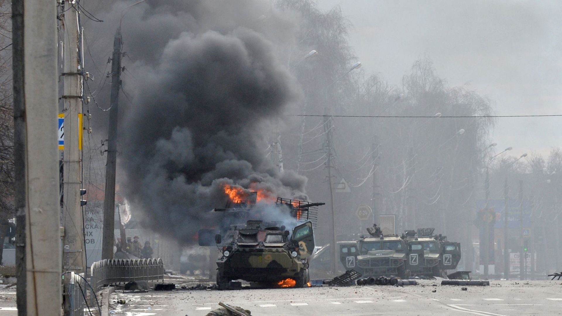 Cette photo prise le 27 février 2022 montre un véhicule blindé de transport de troupes russe brûlant à côté du corps d’un soldat non identifié lors d’un combat avec les forces armées ukrainiennes à Kharkiv.