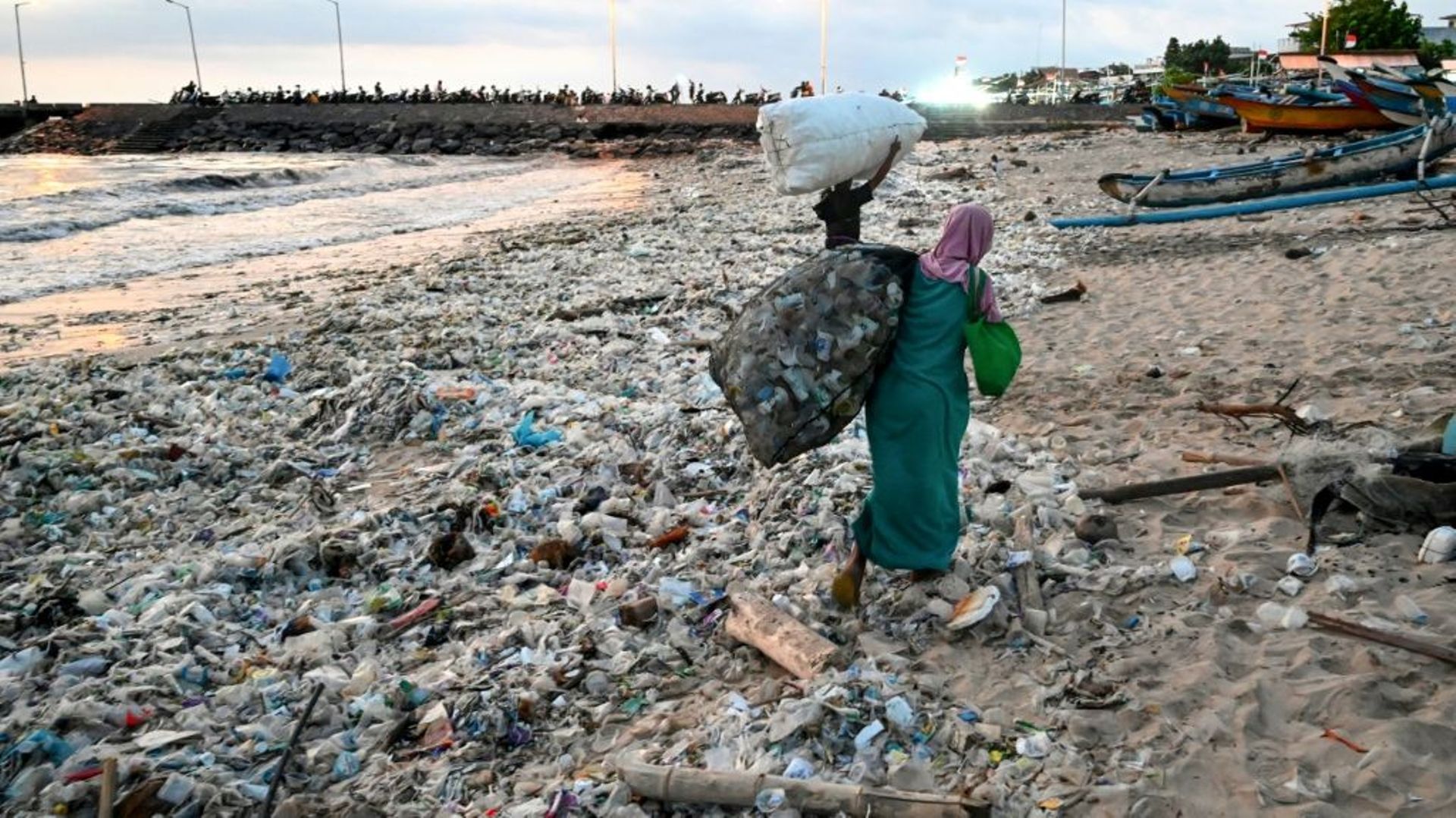 Une femme porte des sacs de déchets recyclables récupérés dans les ordures échouées sur la plage de Kedonganan, sur l’île indonésienne de Bali, le 19 mars 2024.
