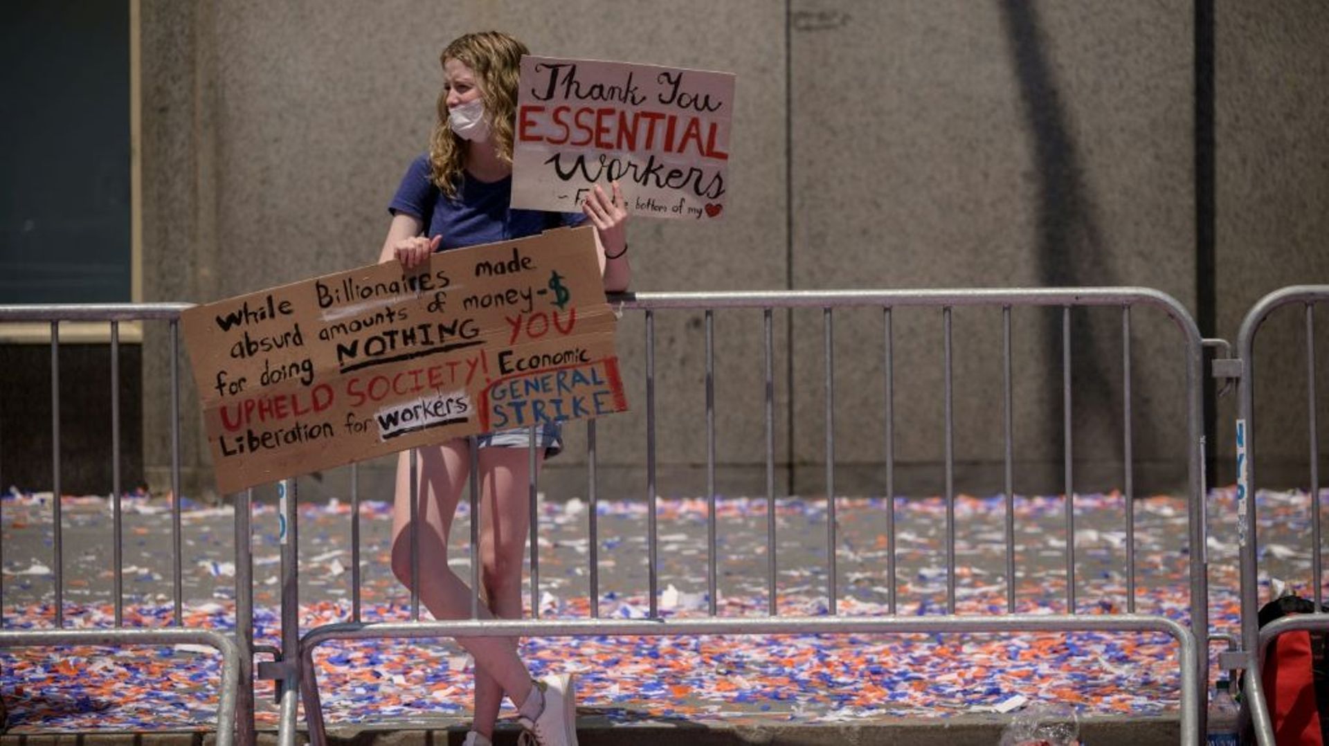 Une spectatrice tient des pancartes pour remercier les "travailleurs essentiels" lors d’une parade en leur honneur, le 7 juillet 2021 à New-York2021