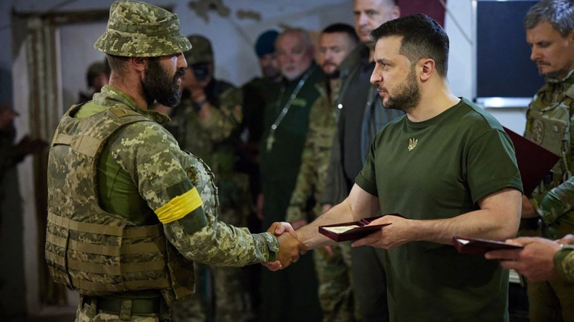 Cette photo prise et publiée par le service de presse de la présidence ukrainienne le 18 juin 2022 montre le président ukrainien Volodymyr Zelensky (R) récompensant un militaire lors de sa visite à la position des troupes ukrainiennes dans la région de My