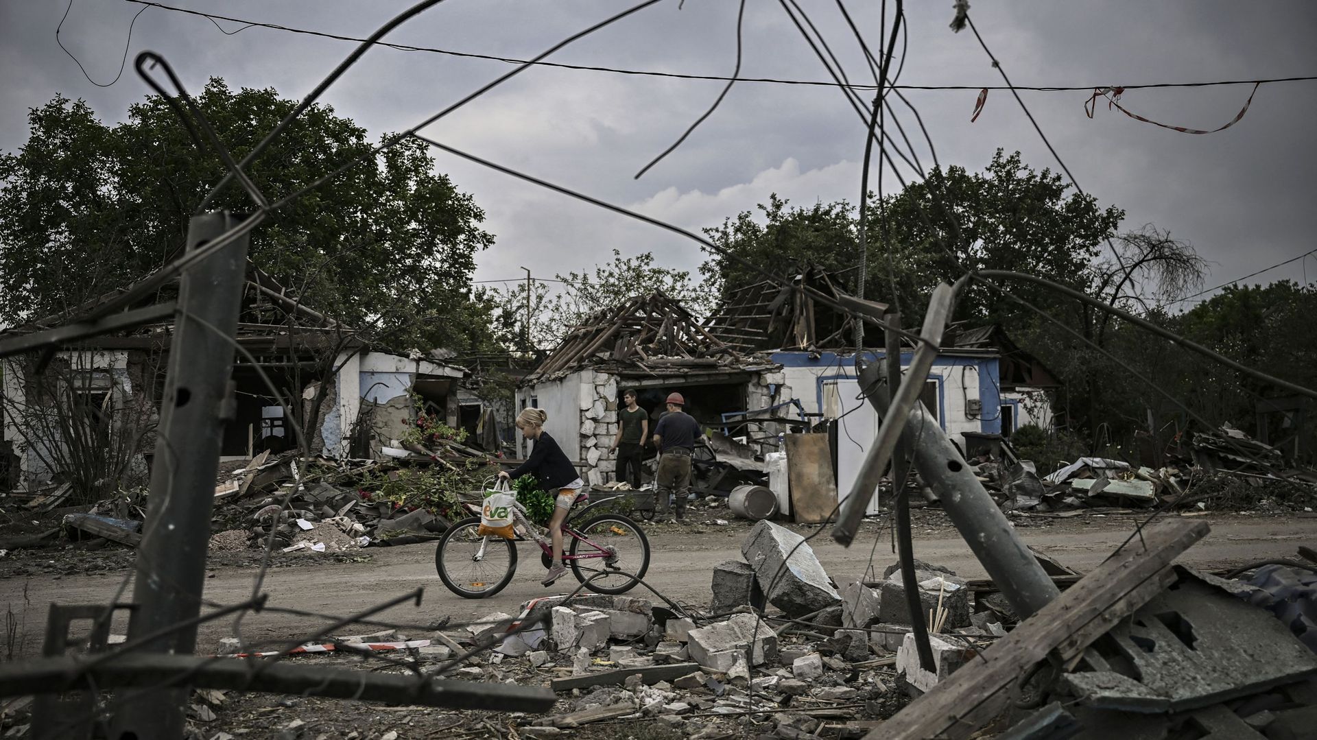 Une jeune fille fait du vélo entre les débris de maisons détruites après une attaque dans la ville de Dobropillya, dans la région de Donbas, dans l'est de l'Ukraine, le 15 juin 2022. 
