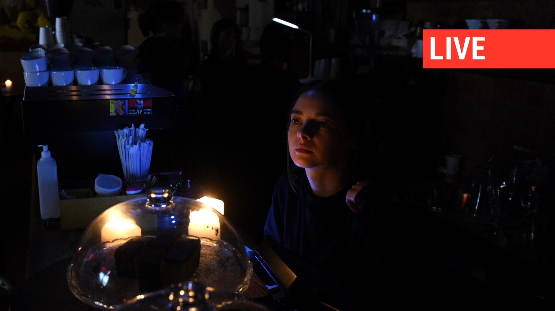 Une barmaid travaille à la lumière d'une bougie dans un café privé d'électricité dans la ville de Lviv, dans l'ouest de l'Ukraine, après le tir de trois missiles russes visant des infrastructures énergétiques, le 11 octobre 2022.