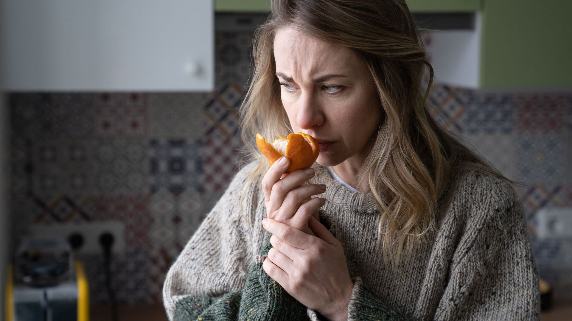 Woman Trying To Sense Smell Of Tangerine Orange, Has Symptoms Of Covid-19 Corona Virus Infection
