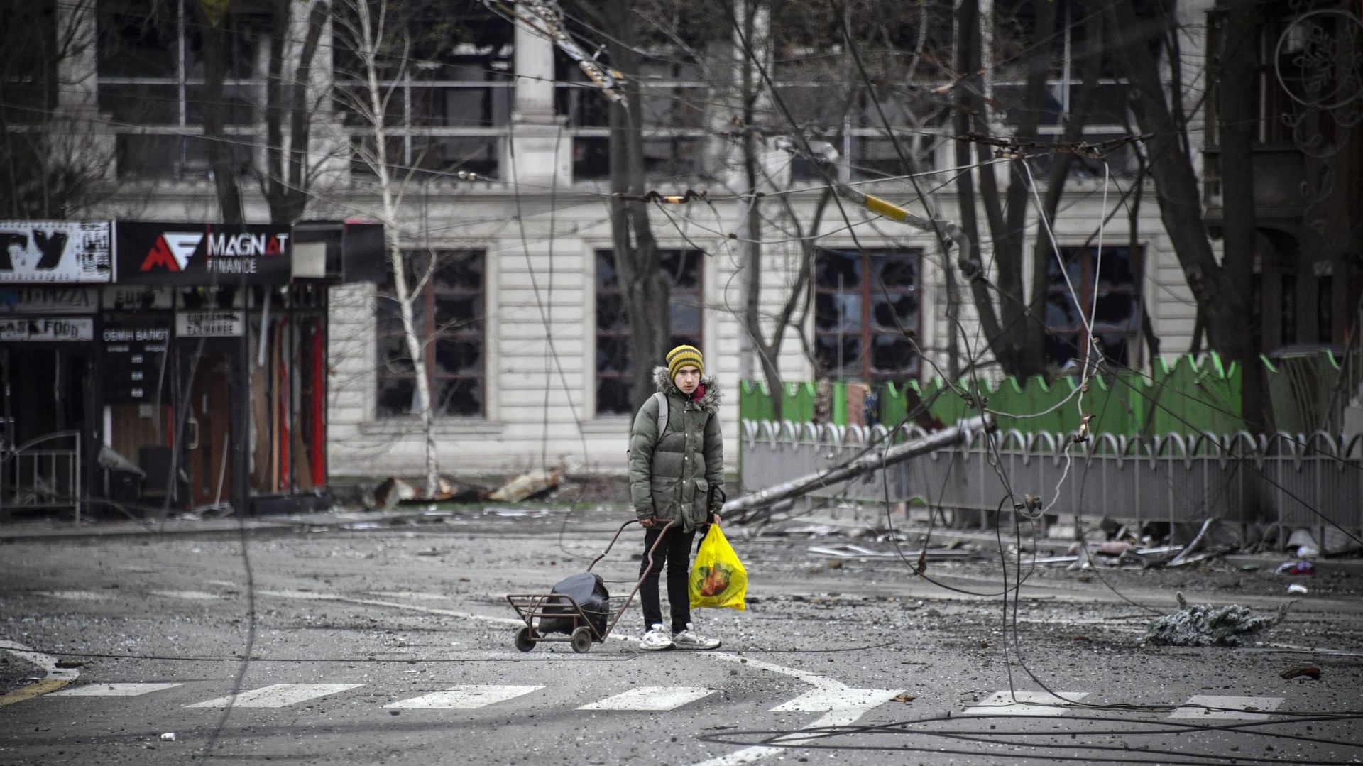 Un jeune homme marche dans une rue de Marioupol, le 12 avril 2022, alors que les troupes russes intensifient leur campagne pour prendre la ville portuaire stratégique, dans le cadre d’un assaut massif prévu dans l’est de l’Ukraine, tandis que le président