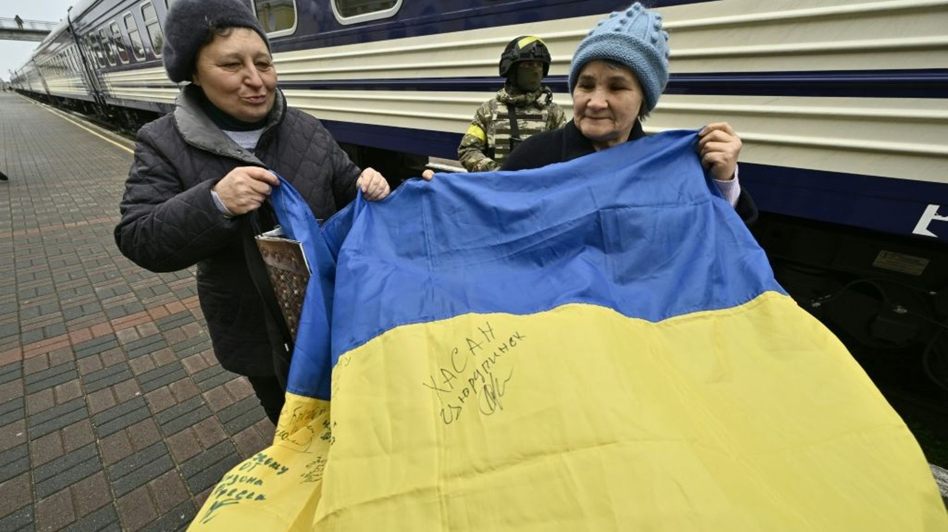 Des habitants de Kherson tiennent le drapeau ukrainien dans la gare de la ville, le 18 novembre 2022