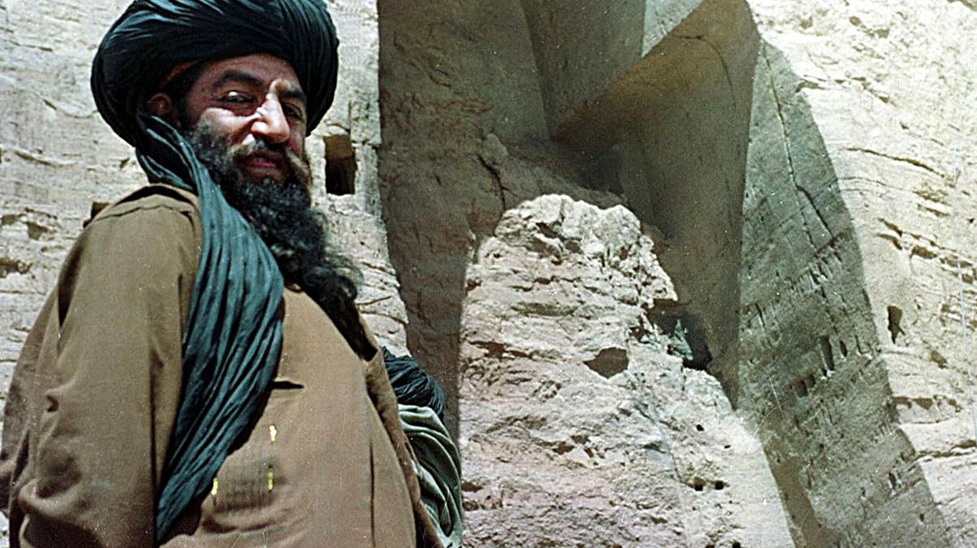 Un taliban pose fièrement devant la niche vide d'un Bouddha détruit