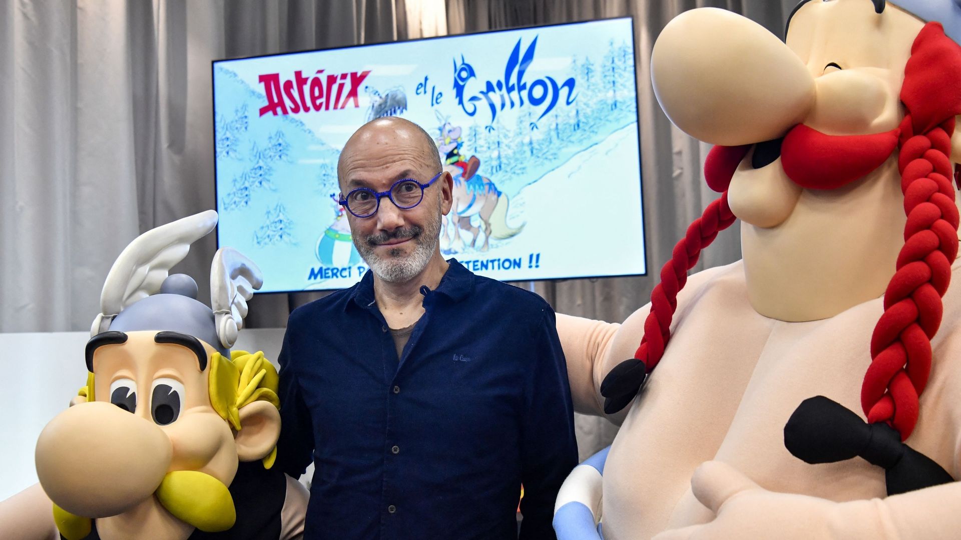L’écrivain et dessinateur français Jean-Yves Ferri pose entre les effigies des personnages de bande dessinée Astérix et Obélix lors de la présentation du nouvel album "Astérix" aux éditions Hachette Livre à Vanves, près de Paris, le 11 octobre 2021. "Asté