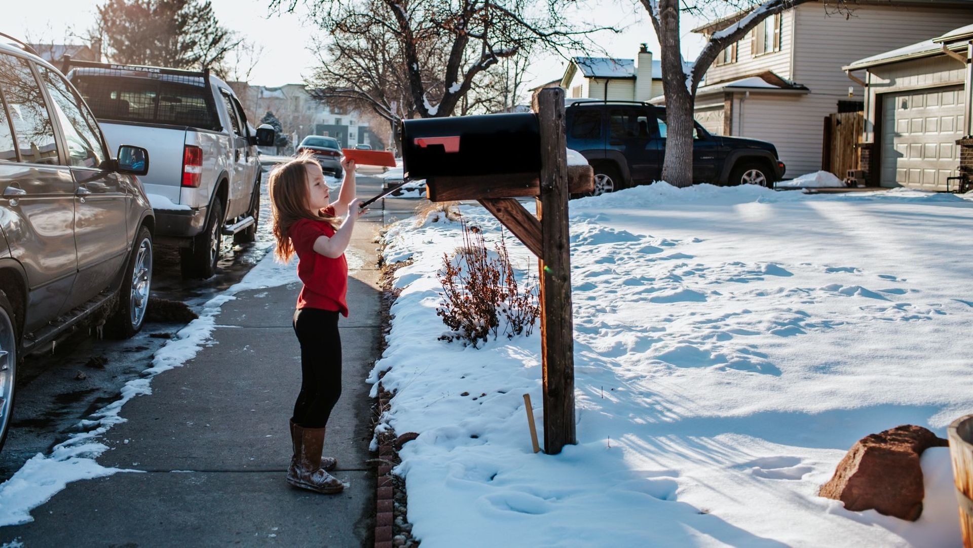 young girl putting letter in mail box