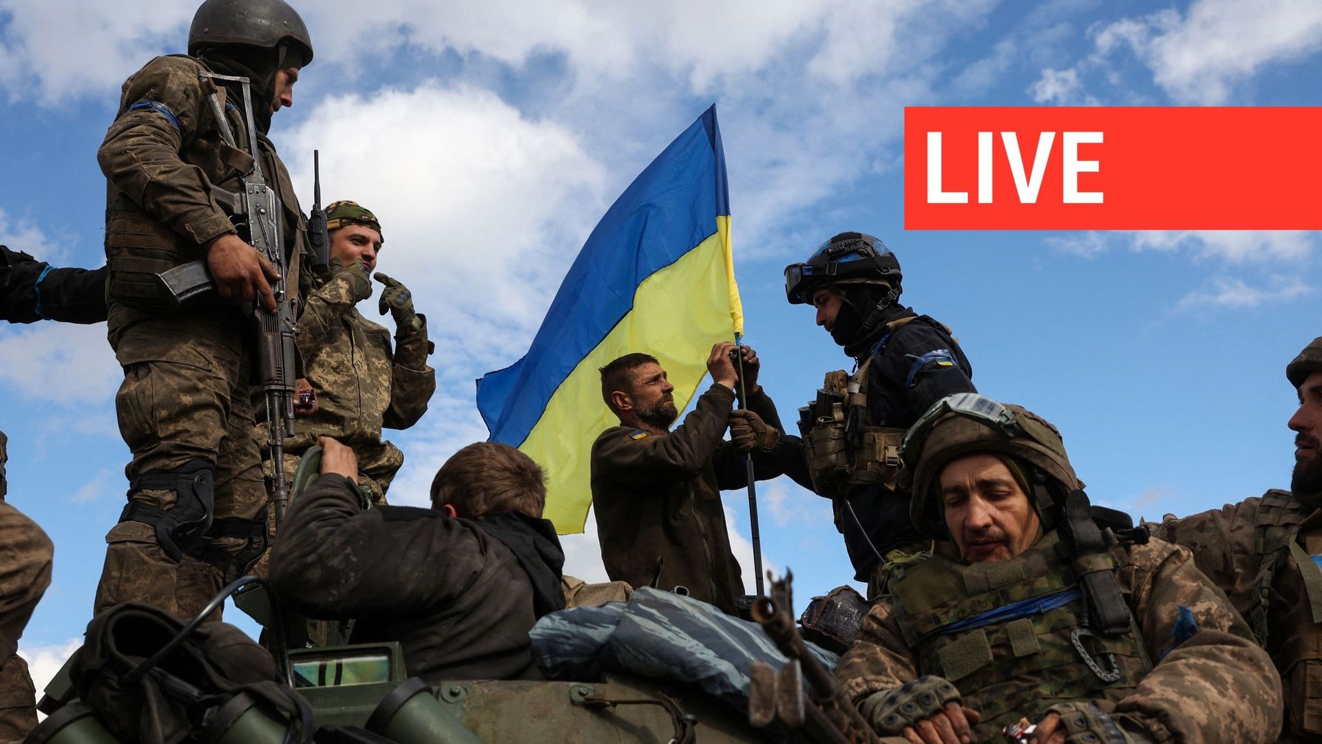Des soldats ukrainiens ajustent un drapeau national au sommet d'un véhicule blindé de transport de troupes sur une route près de Lyman, dans la région de Donetsk, le 4 octobre 2022.