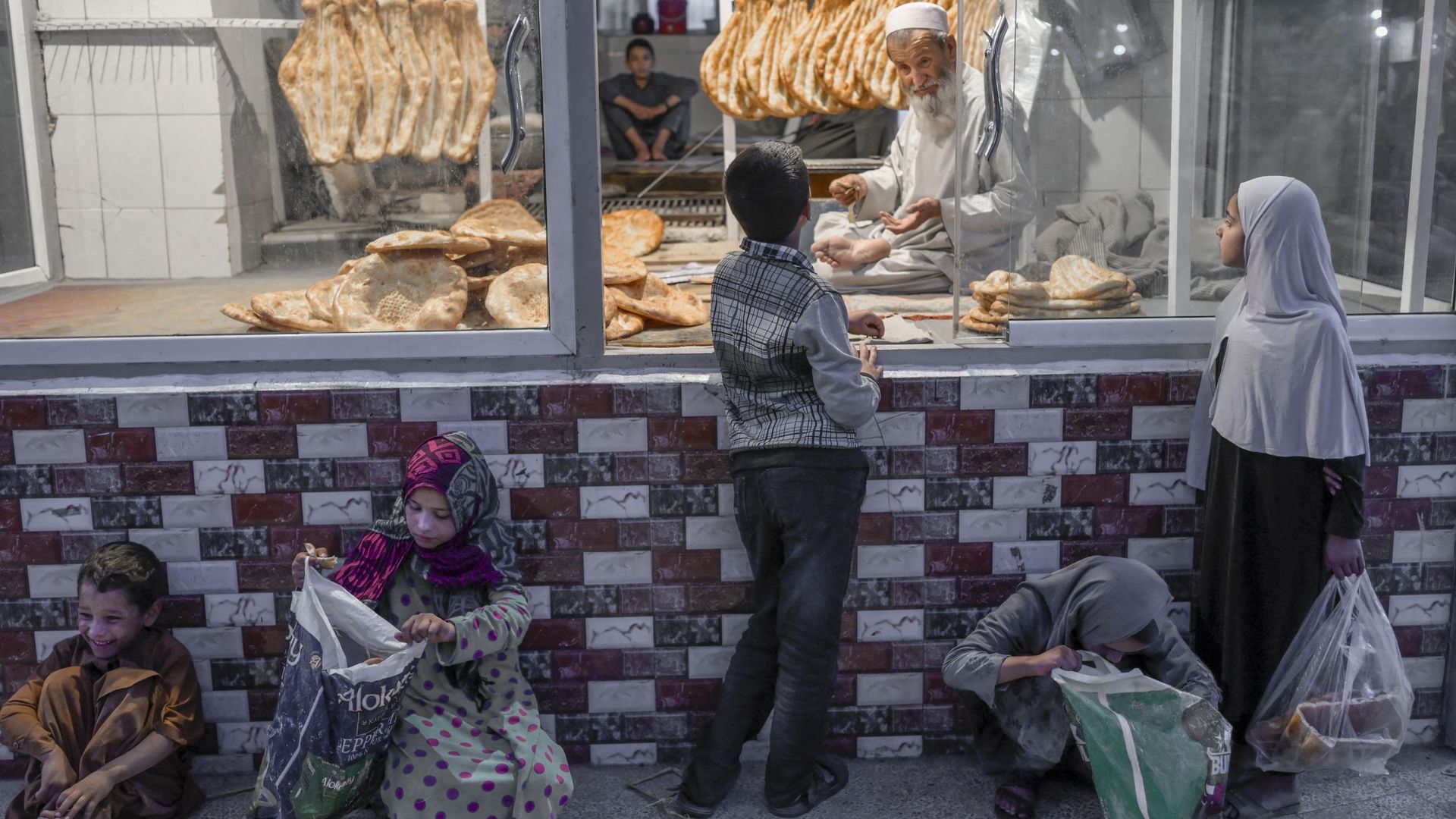 Un enfant achète du pain alors que d’autres attendent qu’on leur en donne gratuitement, à Kaboul ce 14 septembre 2021
