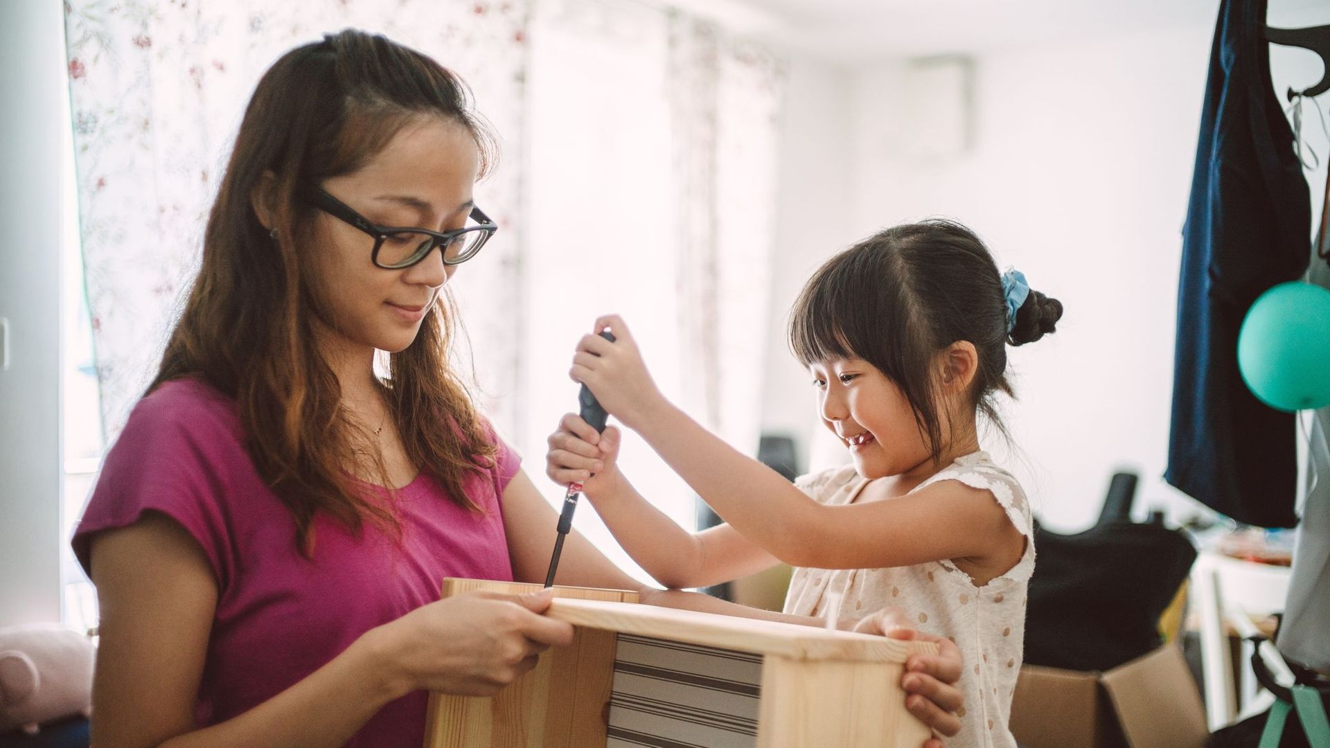 Pretty young mom assembling furnitures with lovely little daughter joyfully