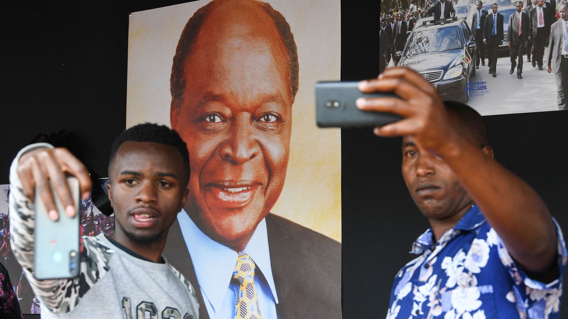 Des personnes en deuil posent à côté de photos de l'ancien président kenyan Mwai Kibaki au Parlement du Kenya, à Nairobi, le 25 avril 2022, où il reposera en chapelle ardente pour permettre aux citoyens de lui rendre hommage.