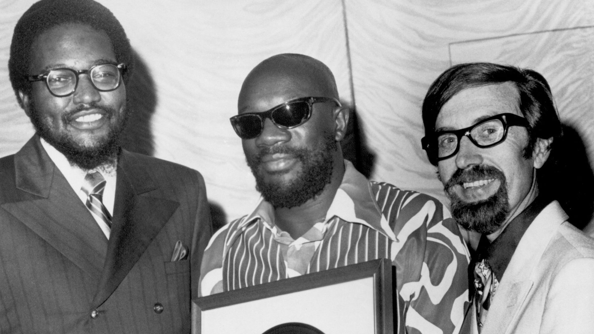 Stax Records executives Al Bell (left) and Jim Stewart (right) present singer and composer Isaac Hayes