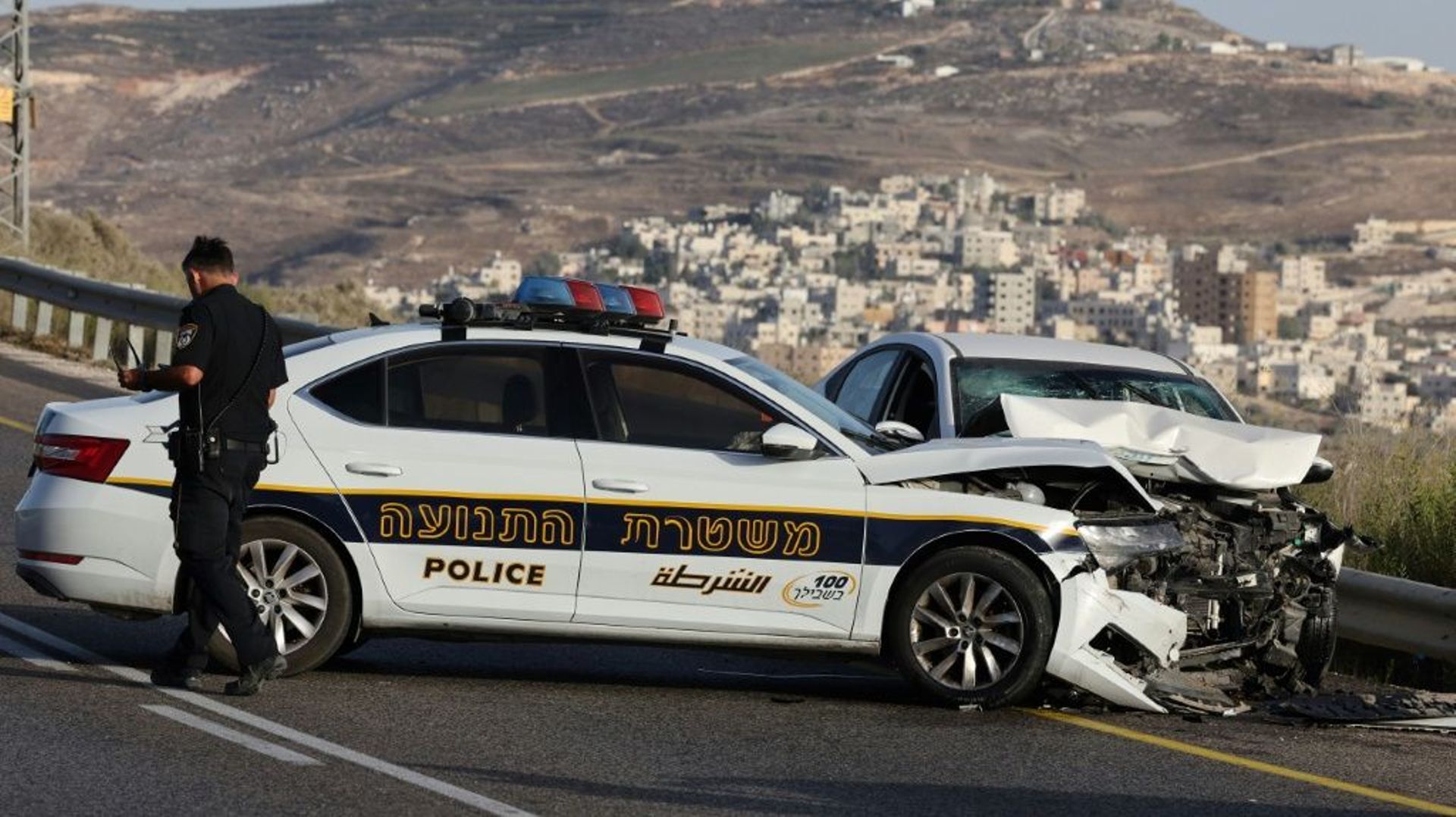 Un policier israélien sur les lieux où un Palestinien a été tué après avoir foncé en voiture sur des soldats israéliens en patrouille, le 24 septembre 2022 à Naplouse, en Cisjordanie occupée
