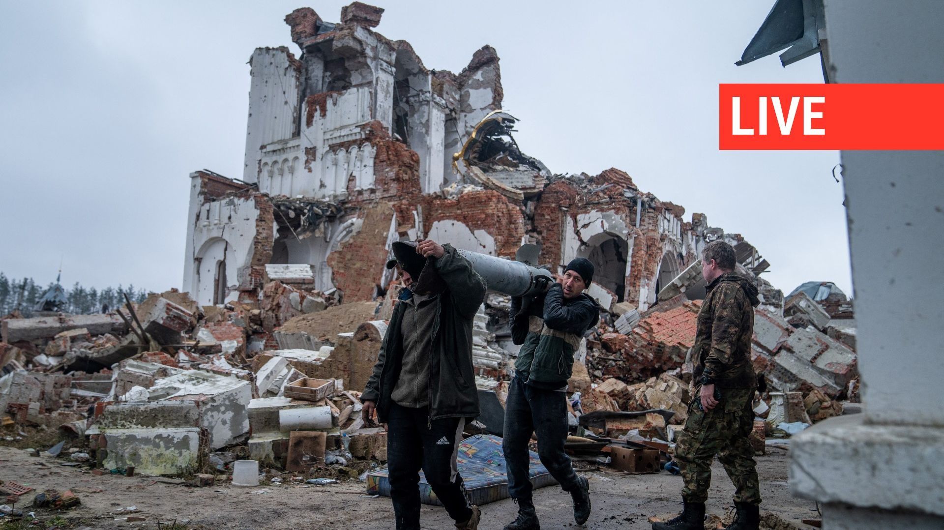 Des bénévoles transportent des restes d'une roquette Uragan alors qu'ils nettoient la zone autour du monastère de la grotte de Sviatohirsk détruit dans un bombardement dans le village de Dolyna, dans la région de Donetsk, le 11 mars 2023.