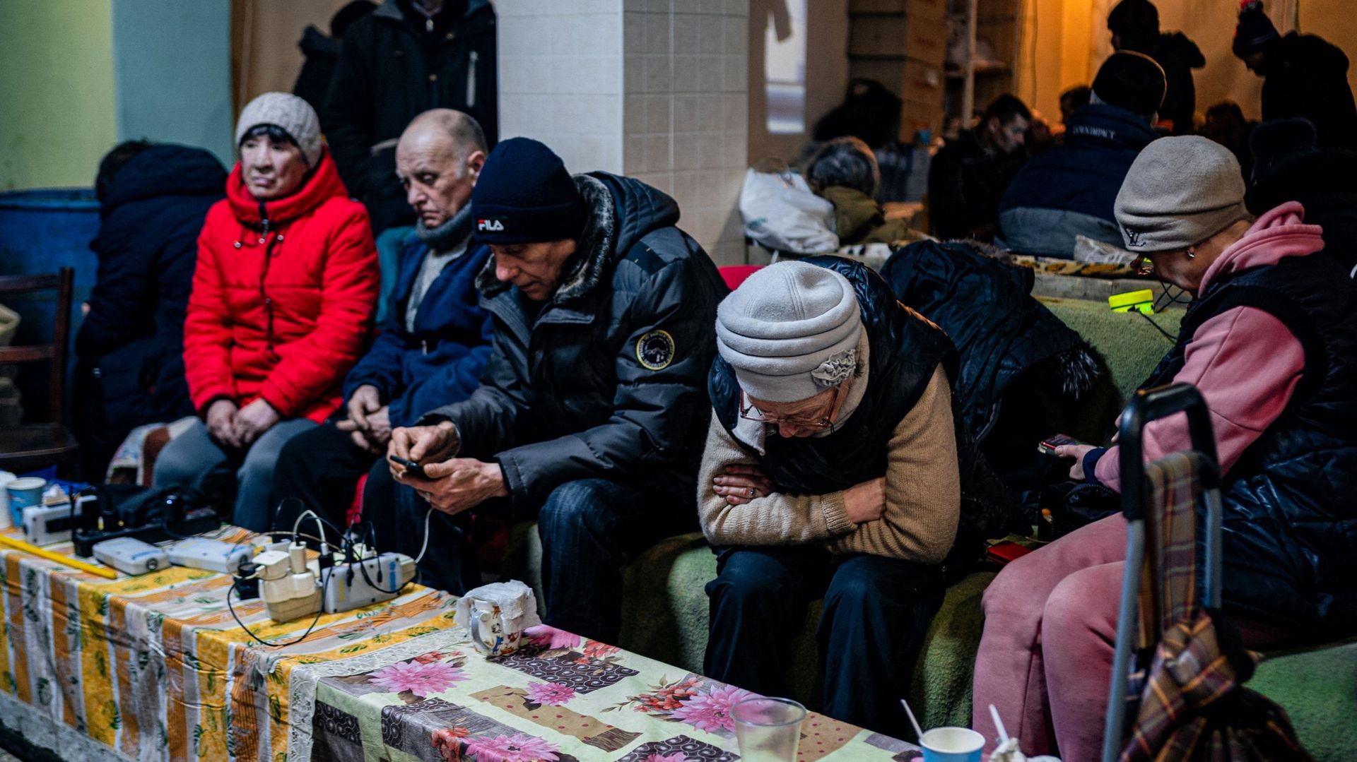 Des Ukrainiens se reposent et consultent leurs téléphones dans un centre d’aide humanitaire à Bakhmout, le 27 février 2023