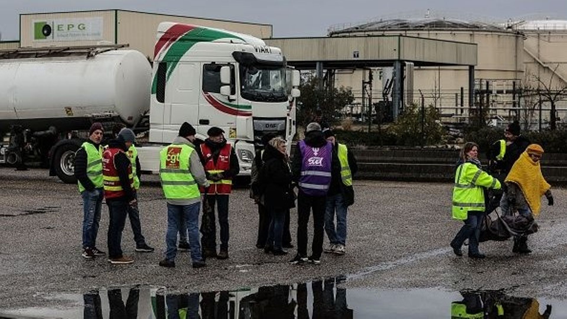 Des manifestants se tiennent devant l'entrepôt pétrolier EPG (Entrepot pétrolier de la Gironde) après avoir levé le blocage à Ambes, dans l'ouest de la France, le 08 mars 2023, au lendemain des rassemblements nationaux organisés depuis le début de l'année
