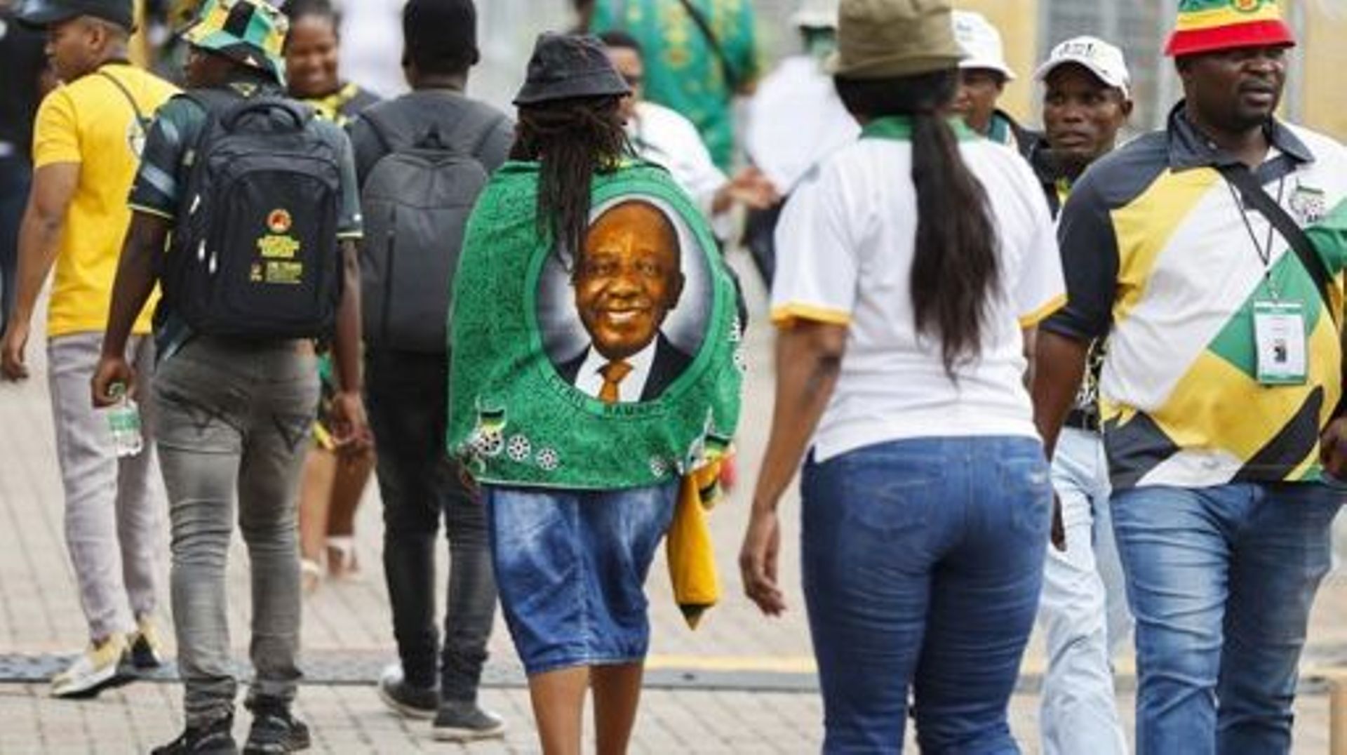 A delegate wearing a fabric printed with the face of South African President Cyril Ramaphosa walk towards the main plenary hall during the third day of the 55th National Conference of the African National Congress (ANC) at the National Recreation Center (