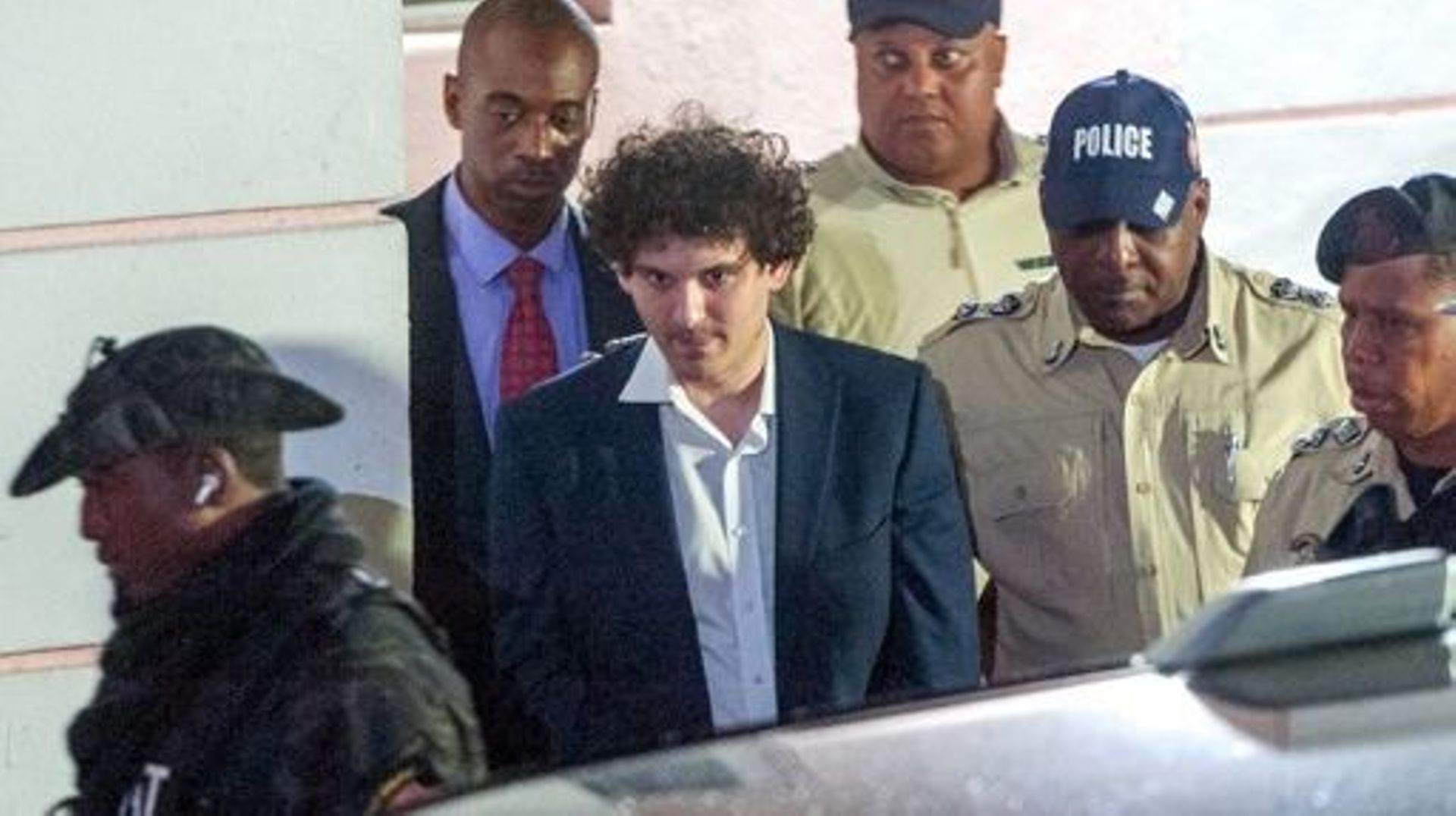 FTX founder Sam Bankman-Fried (C) is led away handcuffed by officers of the Royal Bahamas Police Force in Nassau, Bahamas on December 13, 2022.  Disgraced cryptocurrency tycoon Sam Bankman-Fried was hit with multiple criminal charges December 13, 2022, ac
