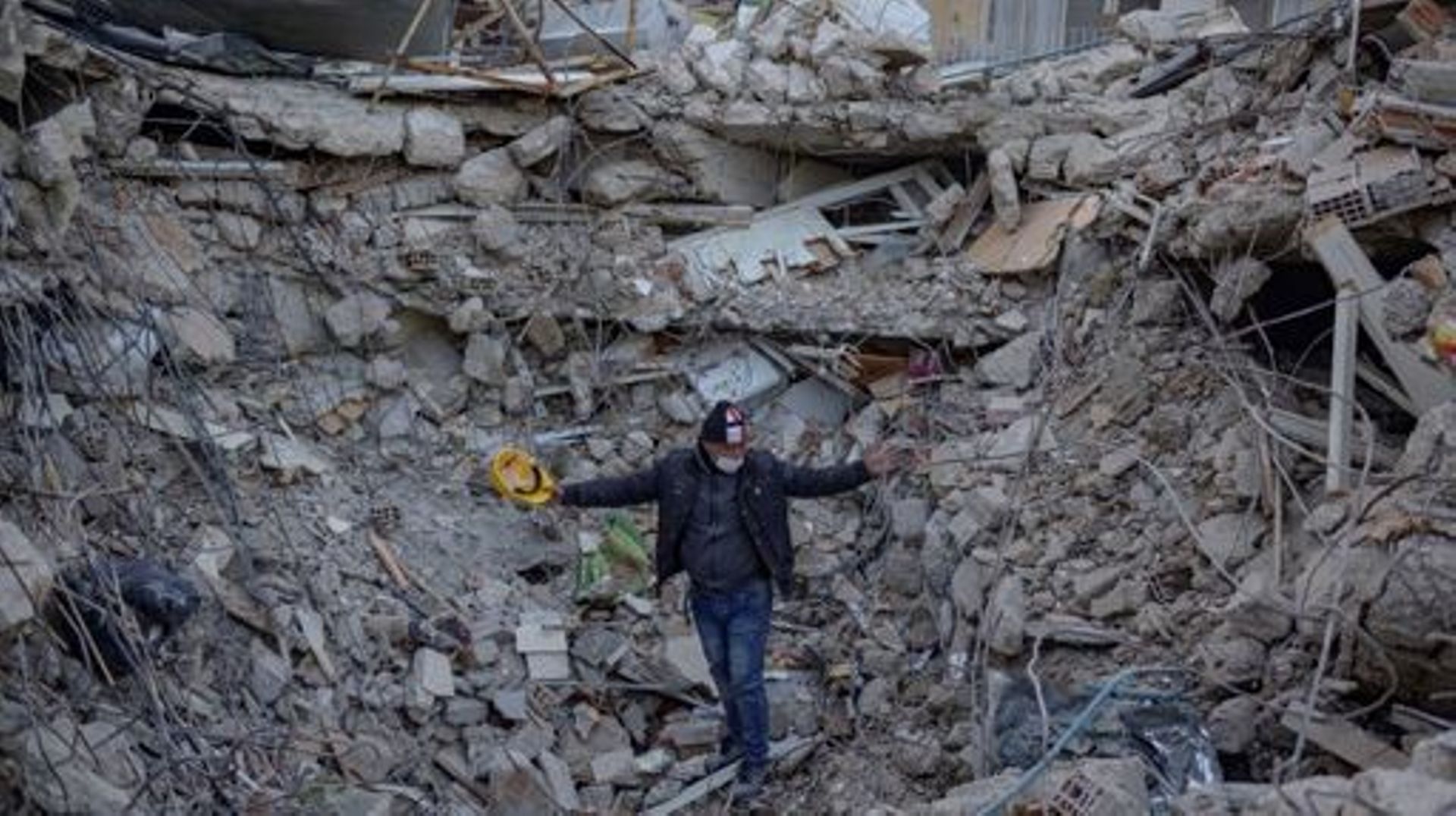 A man stands amid rubble of a collapsed buidling while Greek and Turkish rescuers try to exhume the bodies of six of his relatives, including four children in Antakya, south of Hatay, on February 15, 2023, nine days after a 7,8-magnitude struck the countr