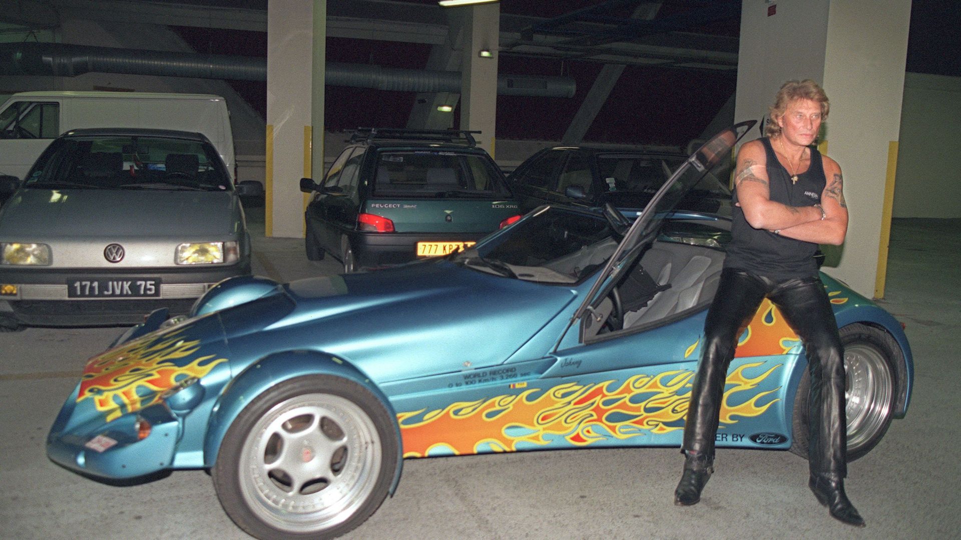 Le chanteur de rock et acteur français Johnny Hallyday pose pour les photographes, le 11 septembre 1995 dans le parking du Palais Omnisport de Paris-Bercy (POPB), aux côtés de la Vertigo dont il vient de faire l'acquisation. 