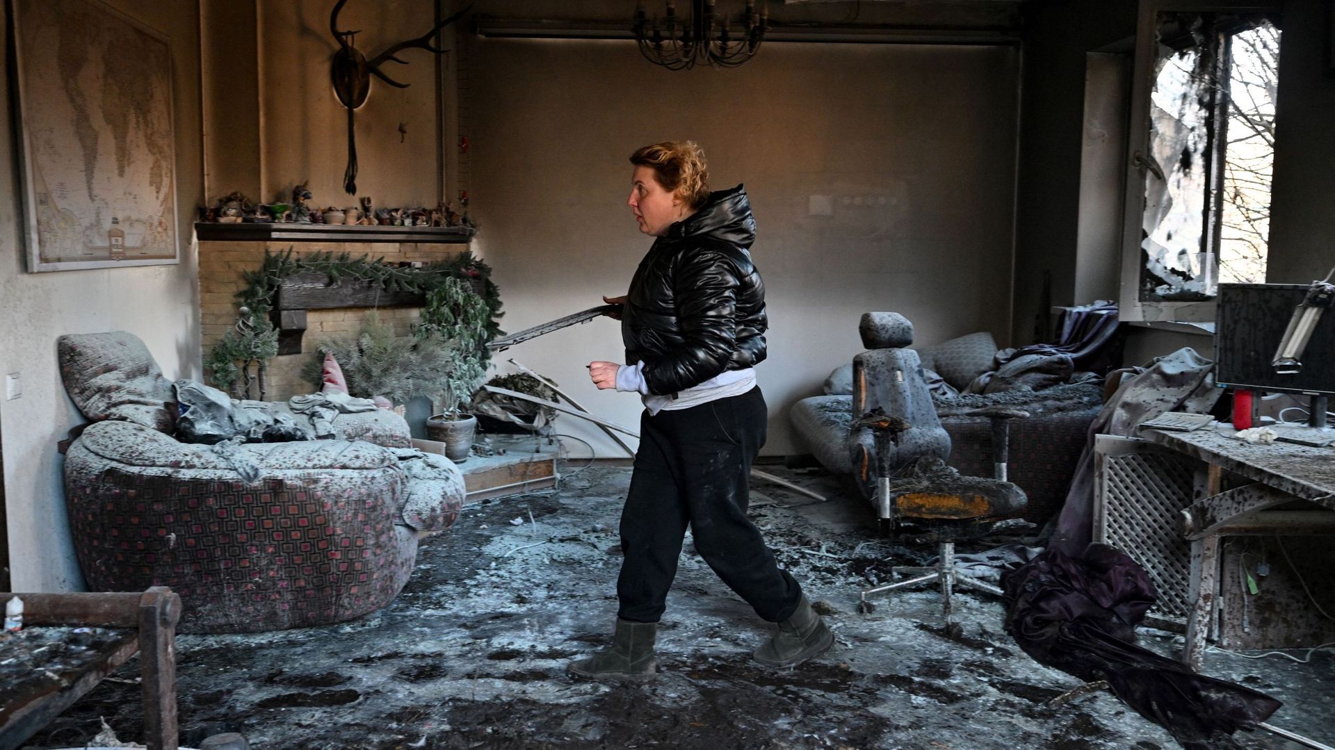 Une femme inspecte des débris à l’intérieur d’une maison privée endommagée par des bombardements dans le quartier d’Osokorky, dans le sud-est de Kiev.