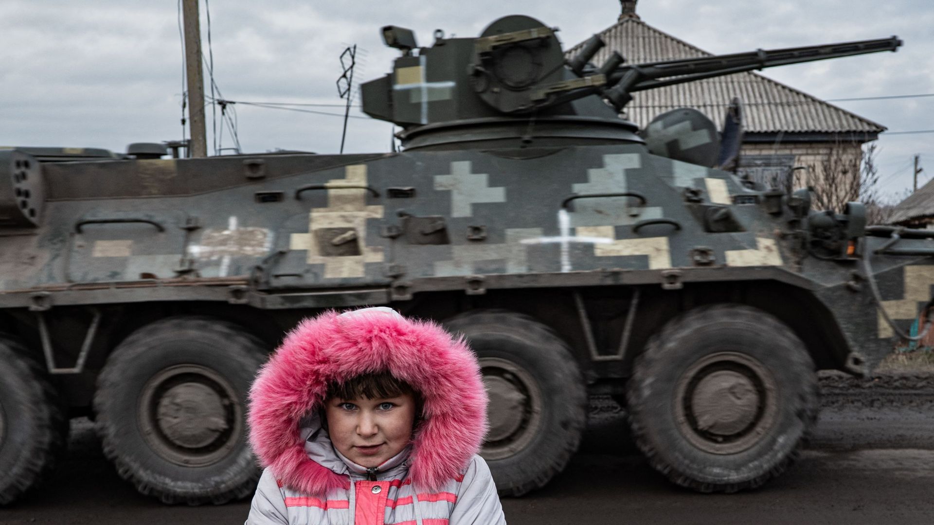 Lisa Shtanko, 8 ans, regarde un véhicule militaire passer devant sa maison dans la ville de Lyman, dans l'est de l'Ukraine, le 23 décembre 2022. 
