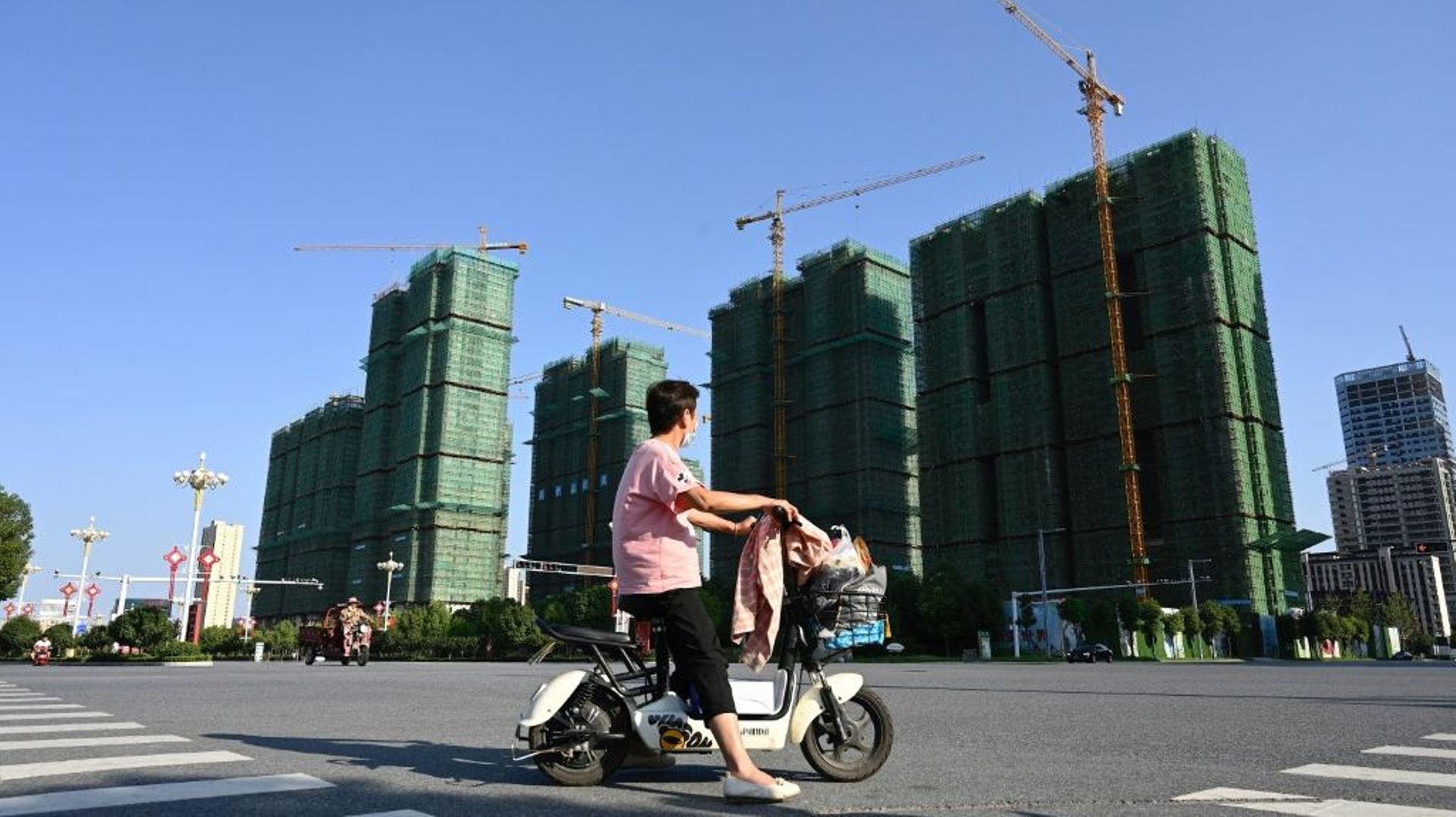 Une femme sur un scooter devant un chantier du promoteur immobilier Evergrande à Zhumadian en Chine, le 14 septembre 2021