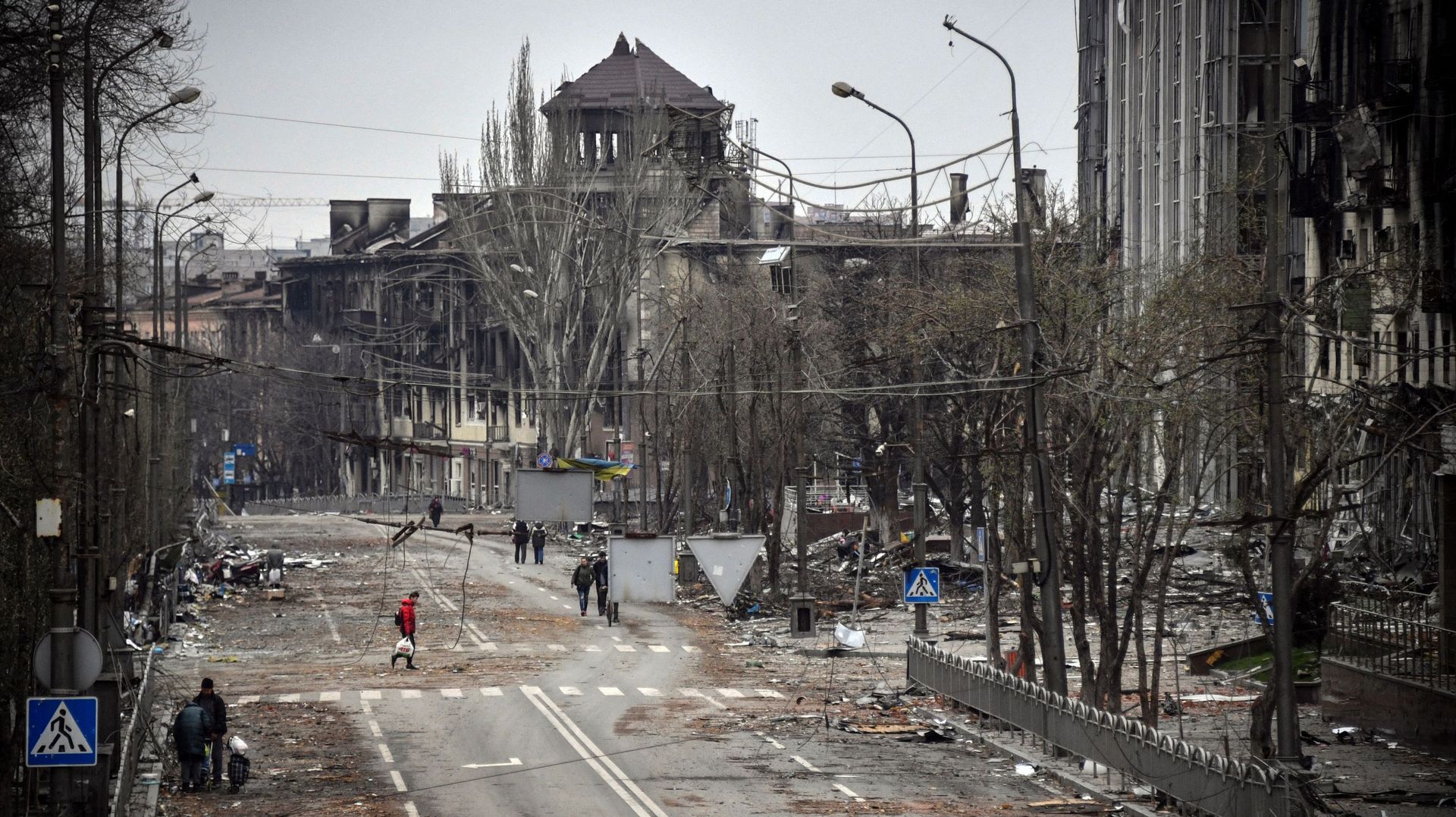 Des personnes marchent dans une avenue de Mariupol, le 12 avril 2022, alors que les troupes russes intensifient leur campagne pour prendre la ville portuaire stratégique, dans le cadre d’une attaque massive prévue dans l’est de l’Ukraine, tandis que le pr