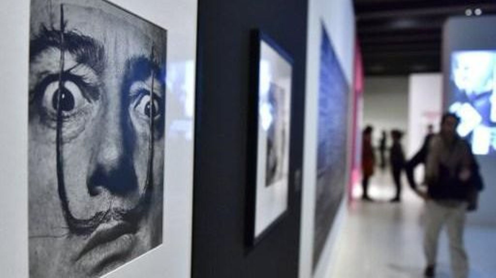 A man walks near a portrait (1953-1954) of late Spanish artist Salvador Dali displayed on a wall during the exhibition Sorprendeme! (Surprise me!), a retrospective on late Latvian born US photographer Philippe Halsman's career at the CaixaForum, in Madrid
