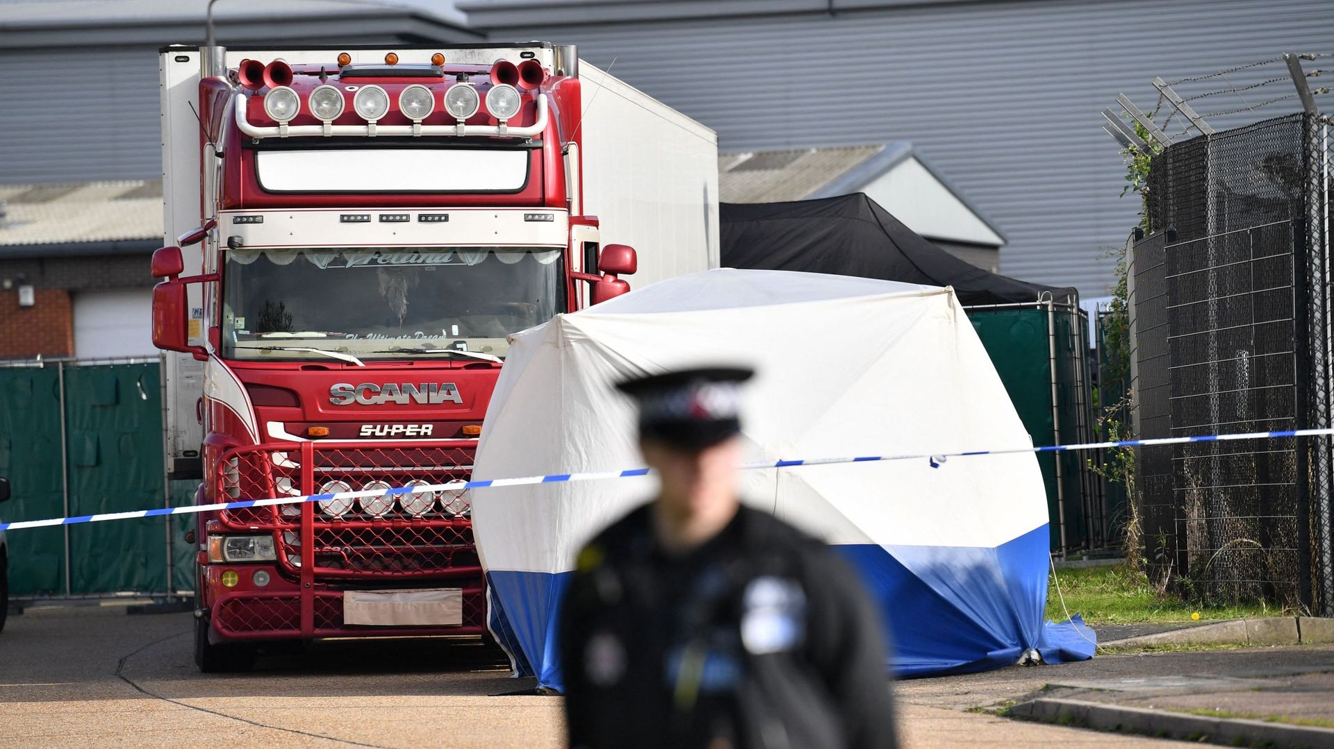 Un officier de police sécurise le cordon sur les lieux où un camion, en provenance de Bulgarie et contenant 39 cadavres, a été découvert dans le parc industriel de Waterglade à Grays, à l'est de Londres, le 23 octobre 2019.