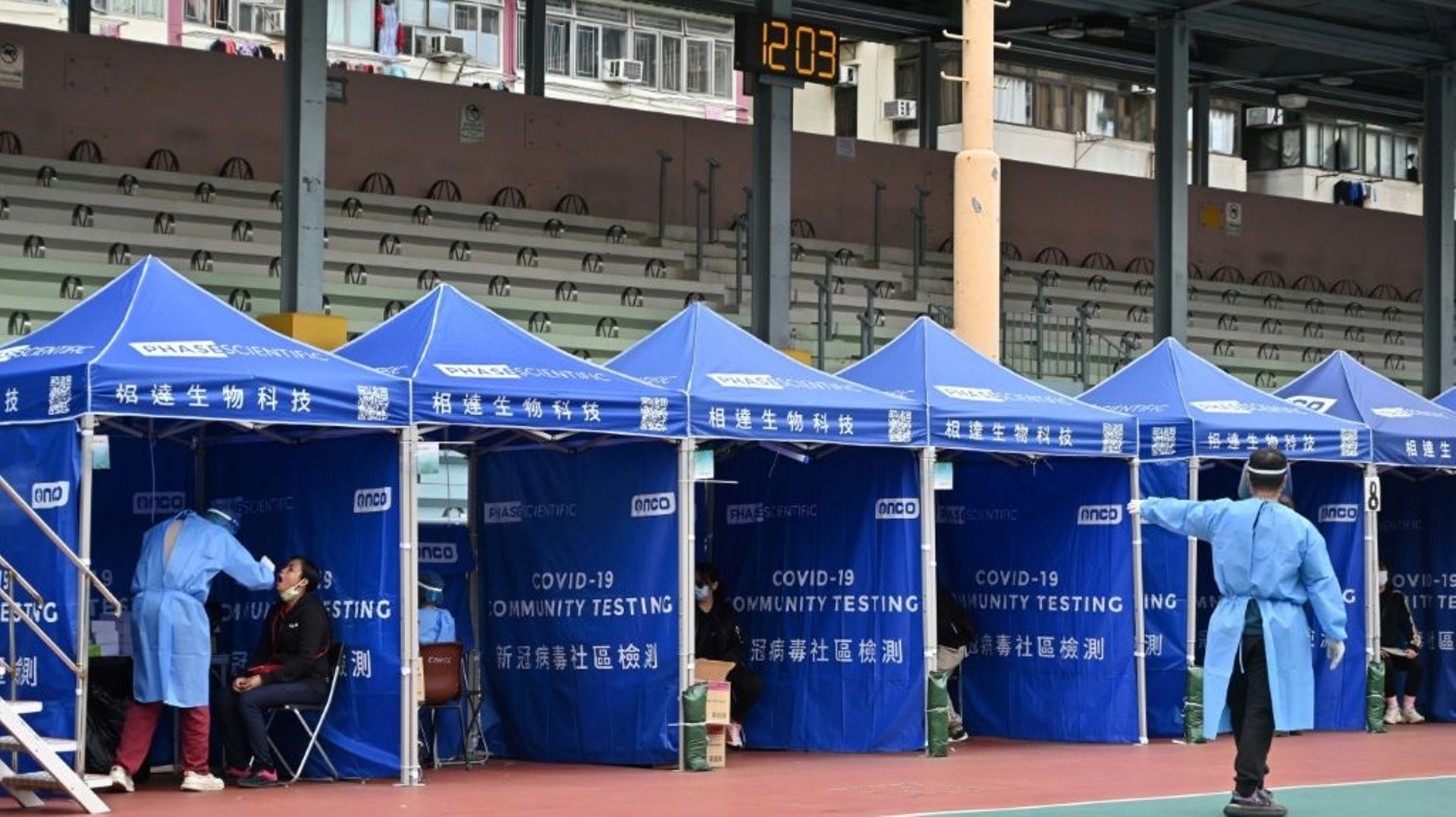 Un responsable indique une place disponible lors d’une opération de dépistage du Covid-19 dans un quartier de Hong Kong après un record d’infections.