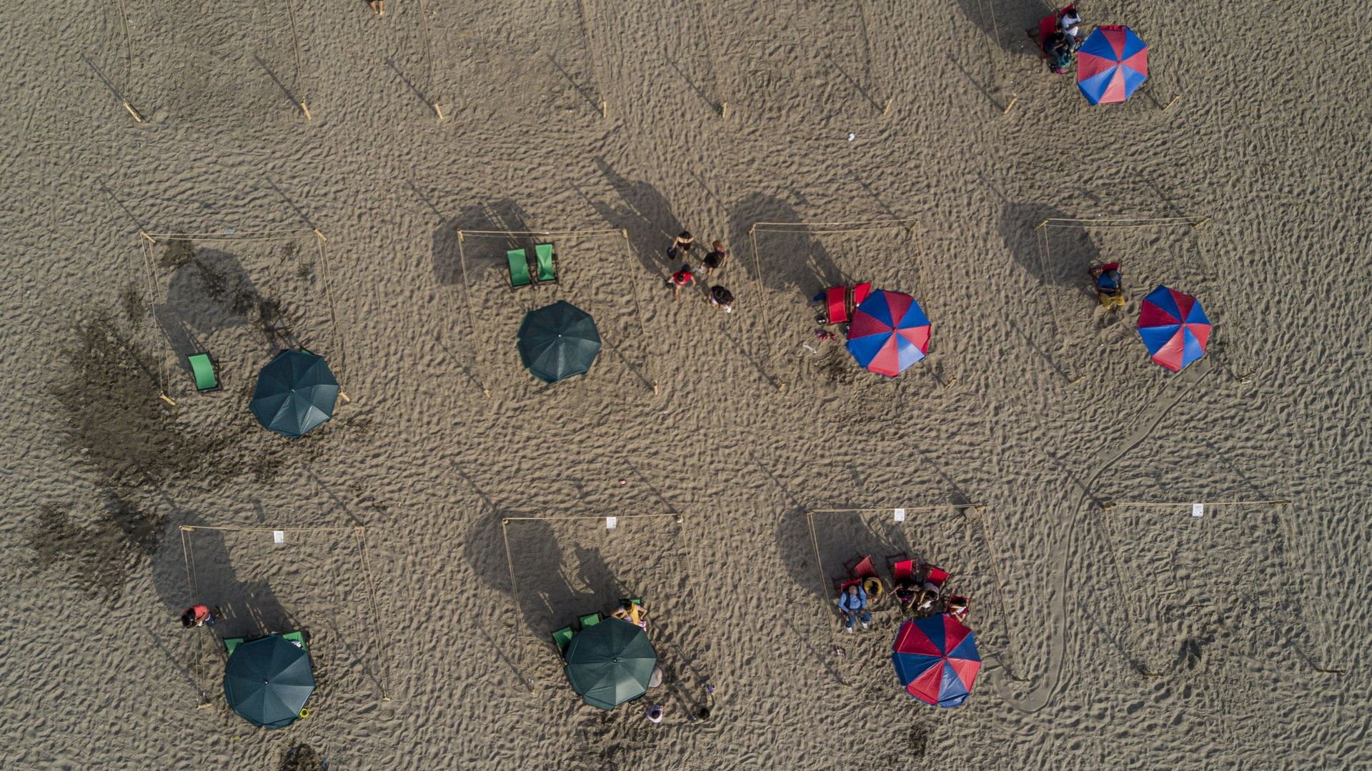Des personnes prennent un bain de soleil à la plage dans des espaces délimités par des cordons pour éviter les foules dans le cadre de la pandémie de nouveau coronavirus COVID-19 à Lima, le 21 décembre 2021.