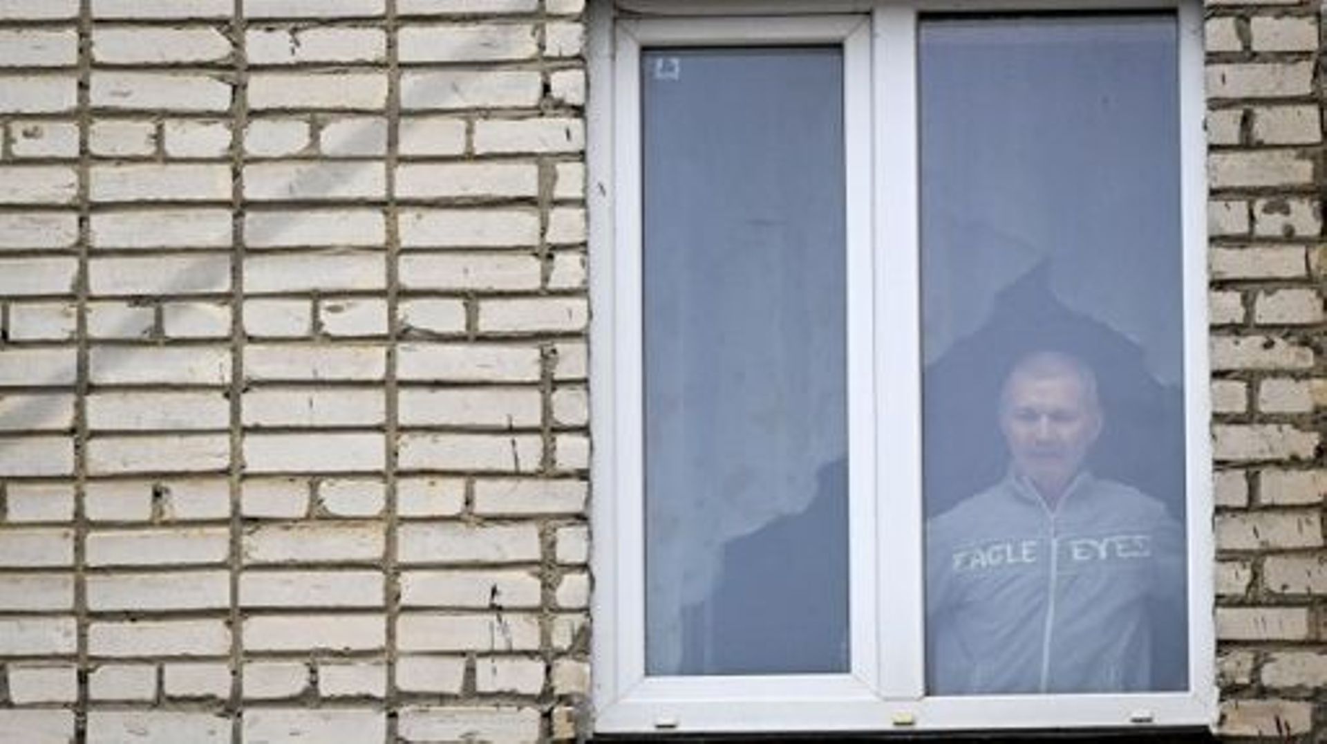 Alexei Moskalyov, 54 ans, parent isolé de Maria Moskalyova, la jeune fille de 13 ans qui a fait un dessin critiquant la campagne militaire de Moscou en Ukraine à l’école en avril de l’année dernière, regarde par la fenêtre de son appartement après qu’il a