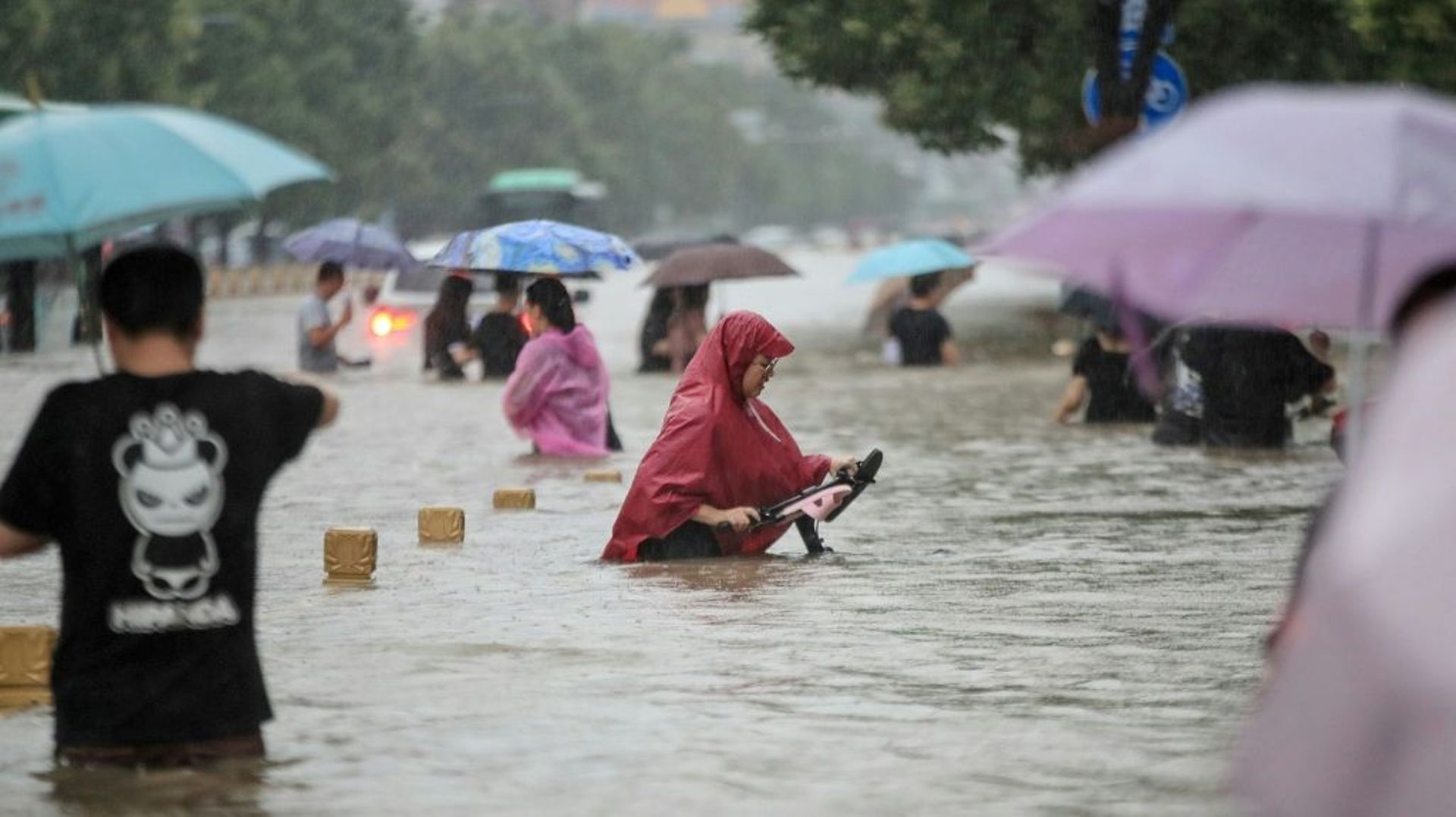 Des habitants de Zhengzhou (Chine) dans une rue de la ville envahie par les eaux, le 20 juillet 2021